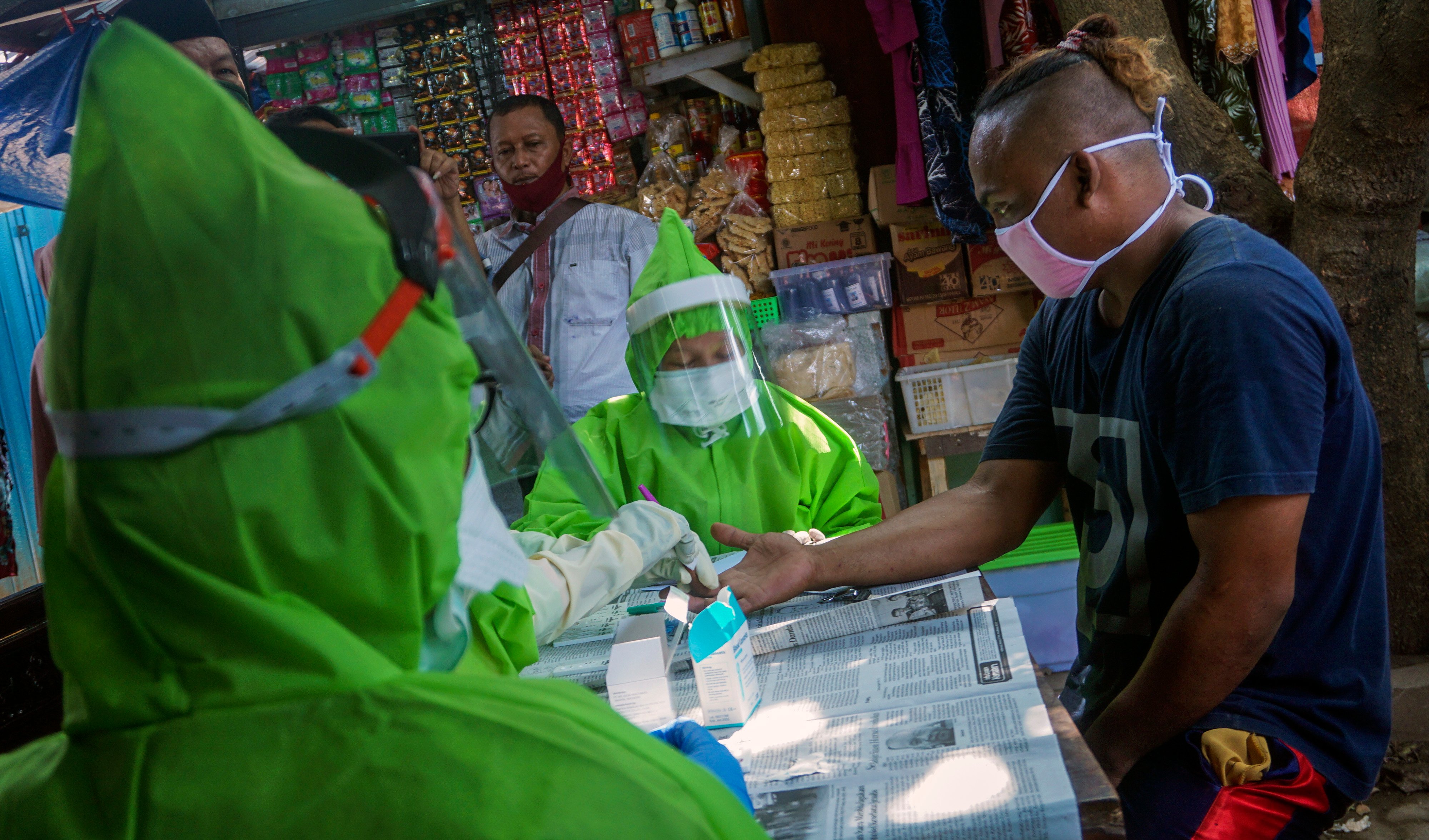 Petugas menggunakan alat pelindung diri (APD) lengkap melakukan tes diagnosa cepat (rapid test) pengunjung di Pasar Sorogenen, Pekalongan