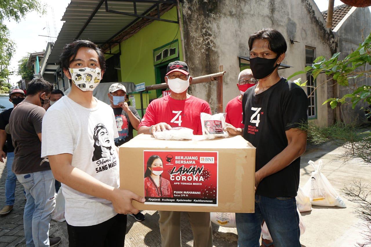 Gibran Rakabuming Raka (kiri) menyalurkan masker bantuan dari Ketua DPR RI Puan Maharani di Solo.