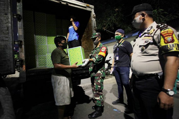 Petugas gabungan menyerahkan bantuan sembako kepada warga sebagai bantuan pangan akibat wabah Covid-19 di RW 03 Kebon Kacang, Jakarta.