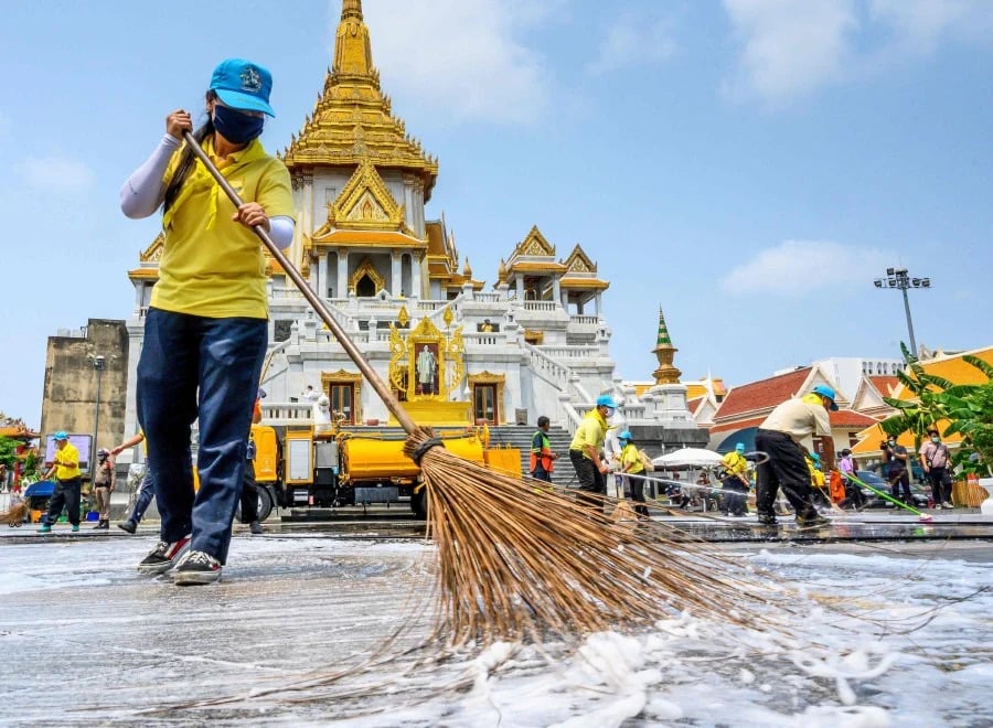  Sukarelawan membersihkan dengan menggunakan disinfektan di sekitar Kuil War Traimit, Bangkok, Thailand.