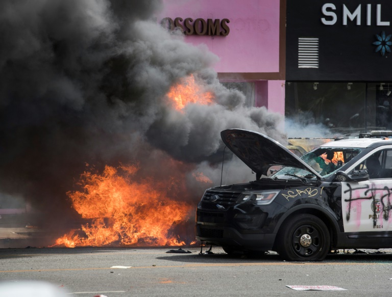 Sejumlah mobil kepolisian dibakar para demonstran saat unjuk rasa di Los Angeles, AS, Sabtu (30/5).   