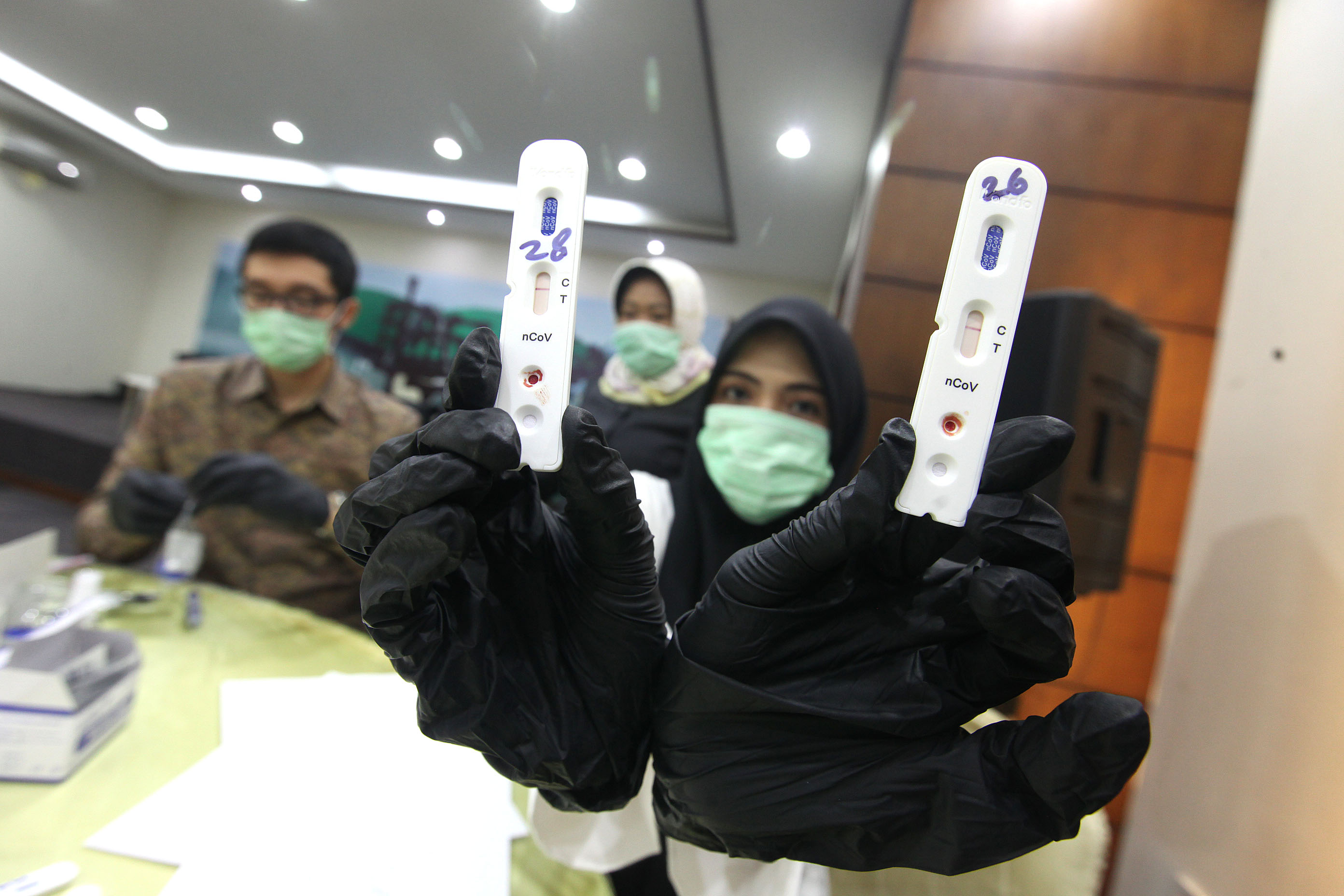 Petugas medis menunjukkan hasil sampel darah saat melakukan rapid test.