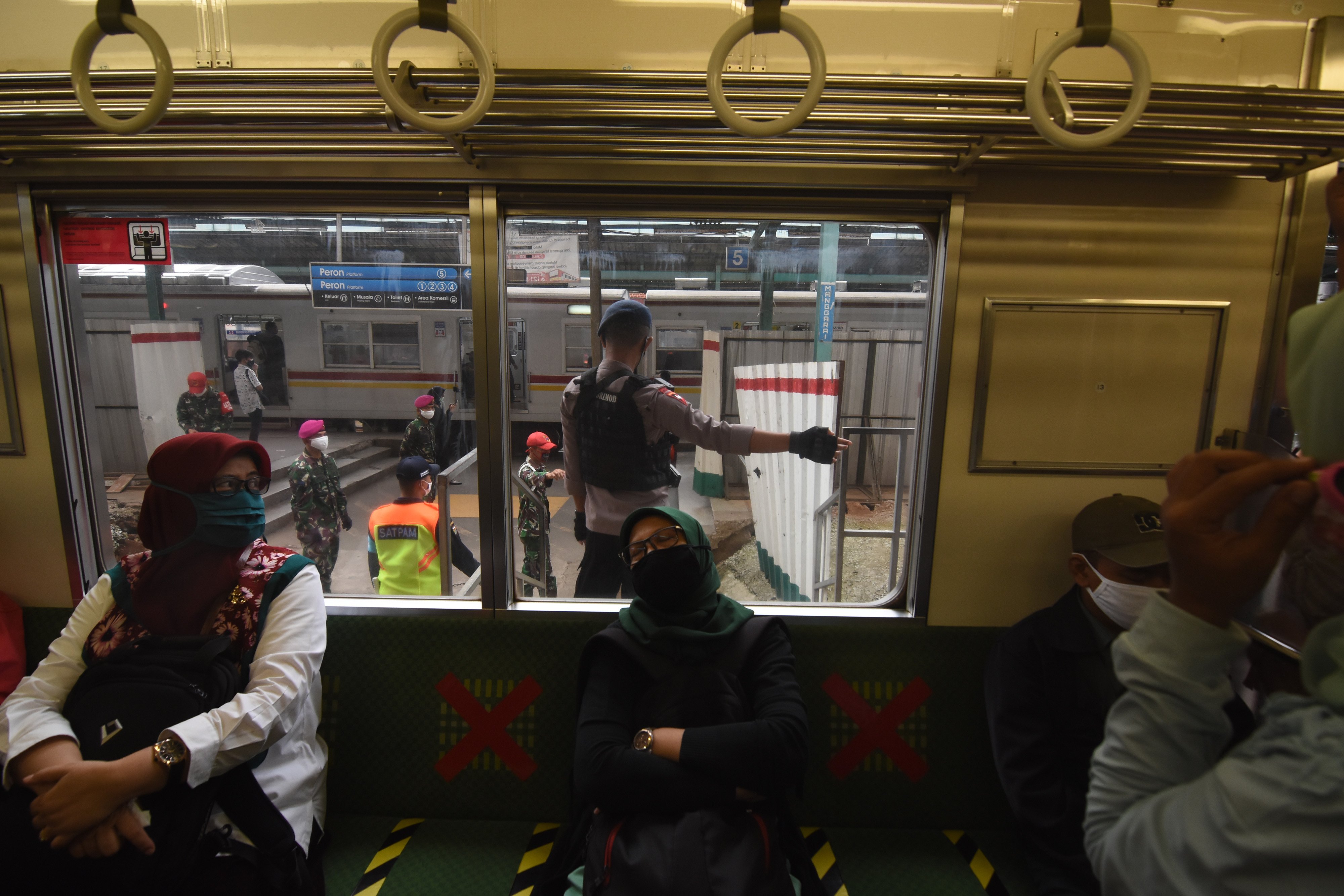 Anggota Polri dan TNI memberikan imbauan soal protokol kesehatan pencegahan covid-19 kepada penumpang KRL di Stasiun Manggarai, Jakarta.