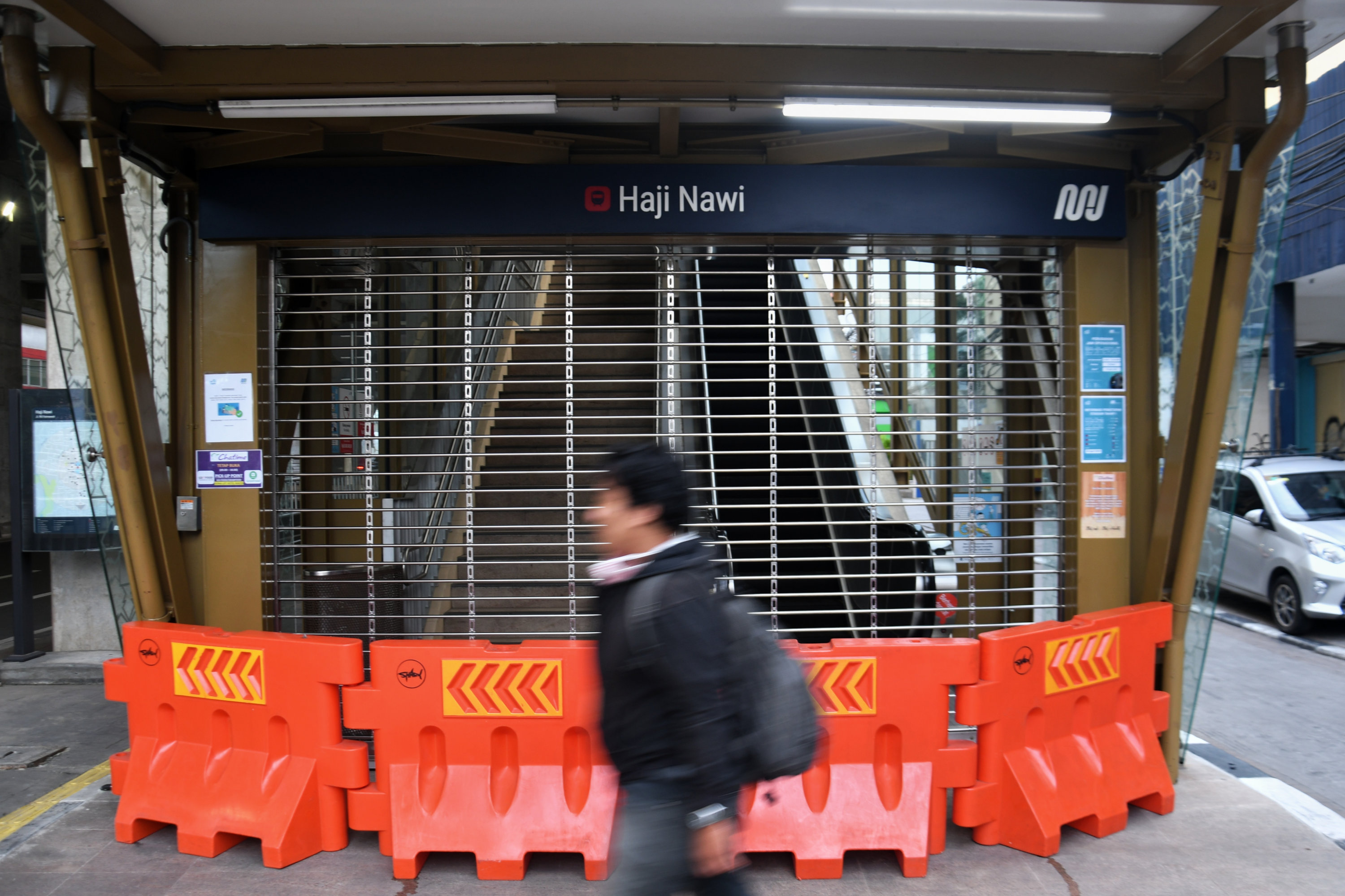 Warga melintas di depan gerbang Stasiun MRT Haji Nawi, Jakarta Selatan, Senin (20/4).