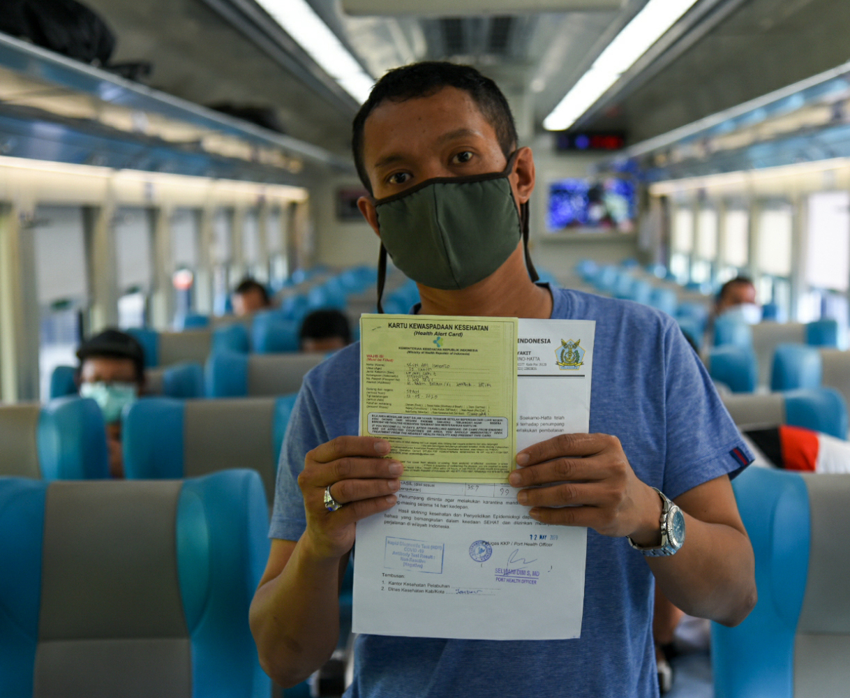 Penumpang memperlihatkan surat pengantar dan keterangan sehat di dalam gerbong KLB relasi Gambir-Surabaya Pasar Turi di Stasiun Gambir.