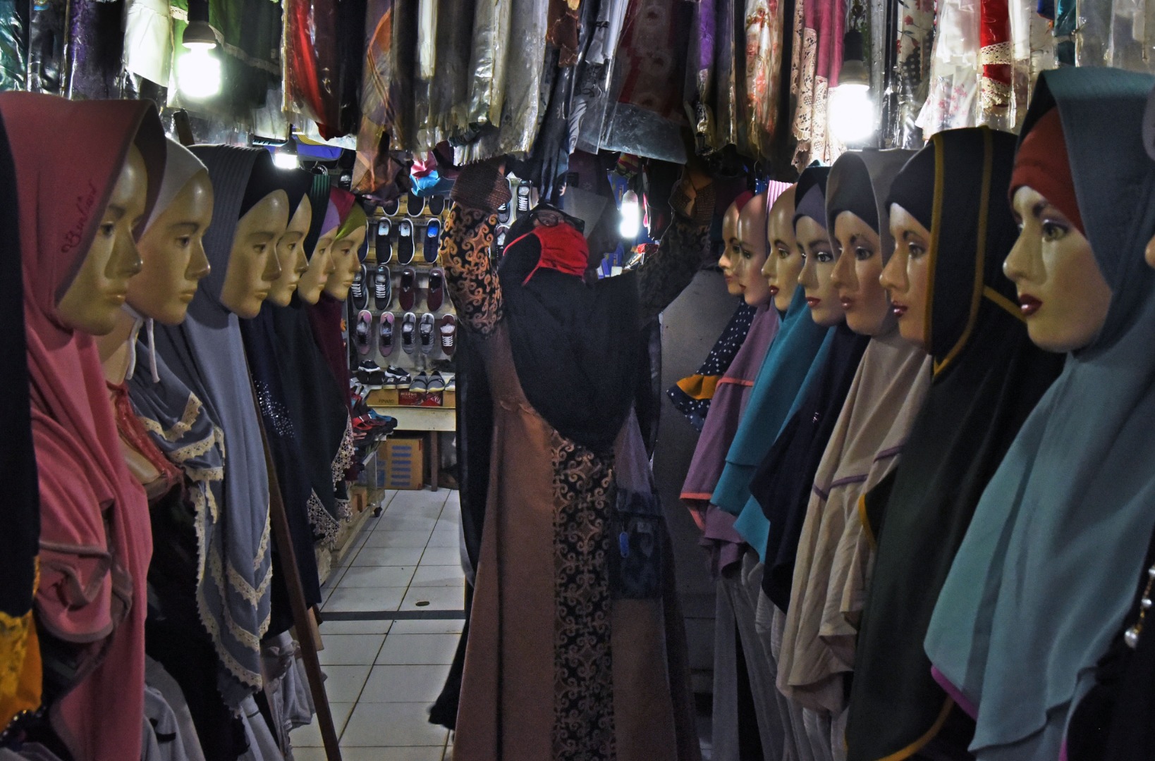 Konsumen memilih busana muslim di tengah pasar yang sepi.