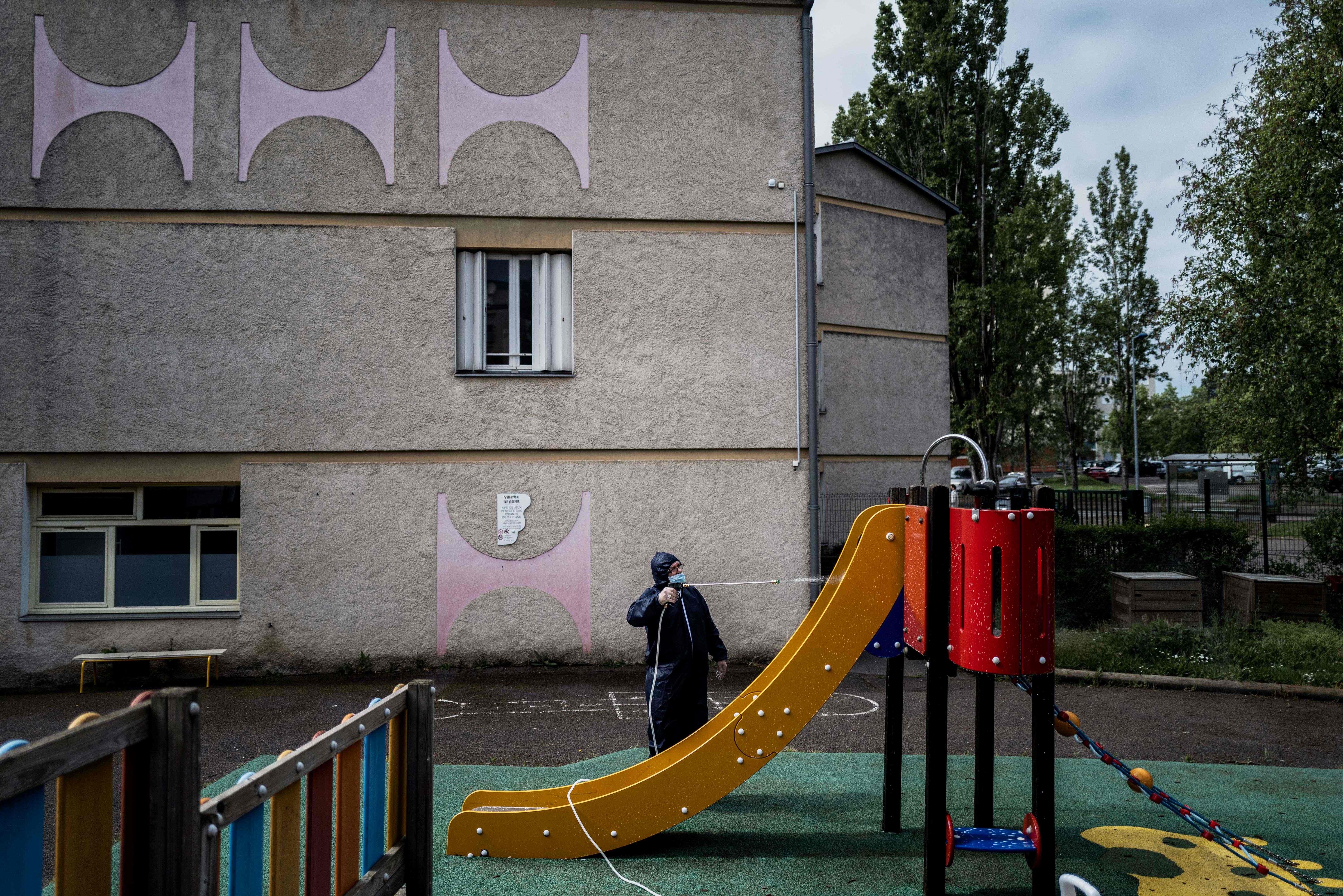 Seorang petugas menyemprotkan disinfektan di taman bermain di sebuah sekolah di Beaune, Prancis.