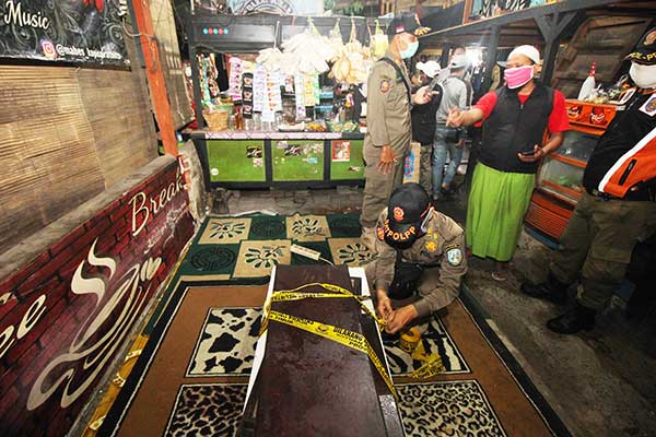 Petugas menyegel meja dan kursi sebuah kafe saat razia pembatasan aktivitas malam hari di kawasan Simo Gunung, Surabaya, Jawa Timur.