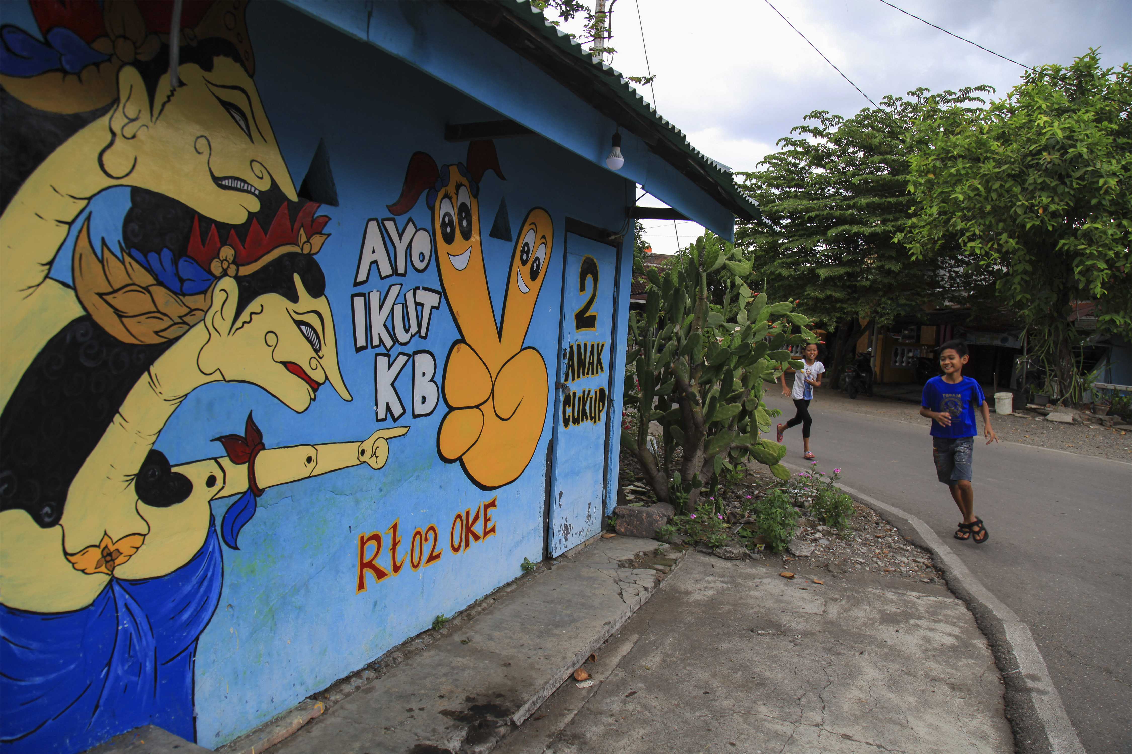 Dua anak melintas di depan mural kampanye program Keluarga Berencana, di Kampung KB, Pucang Sawit, Solo Jawa Tengah, Selasa (14/11) lalu.