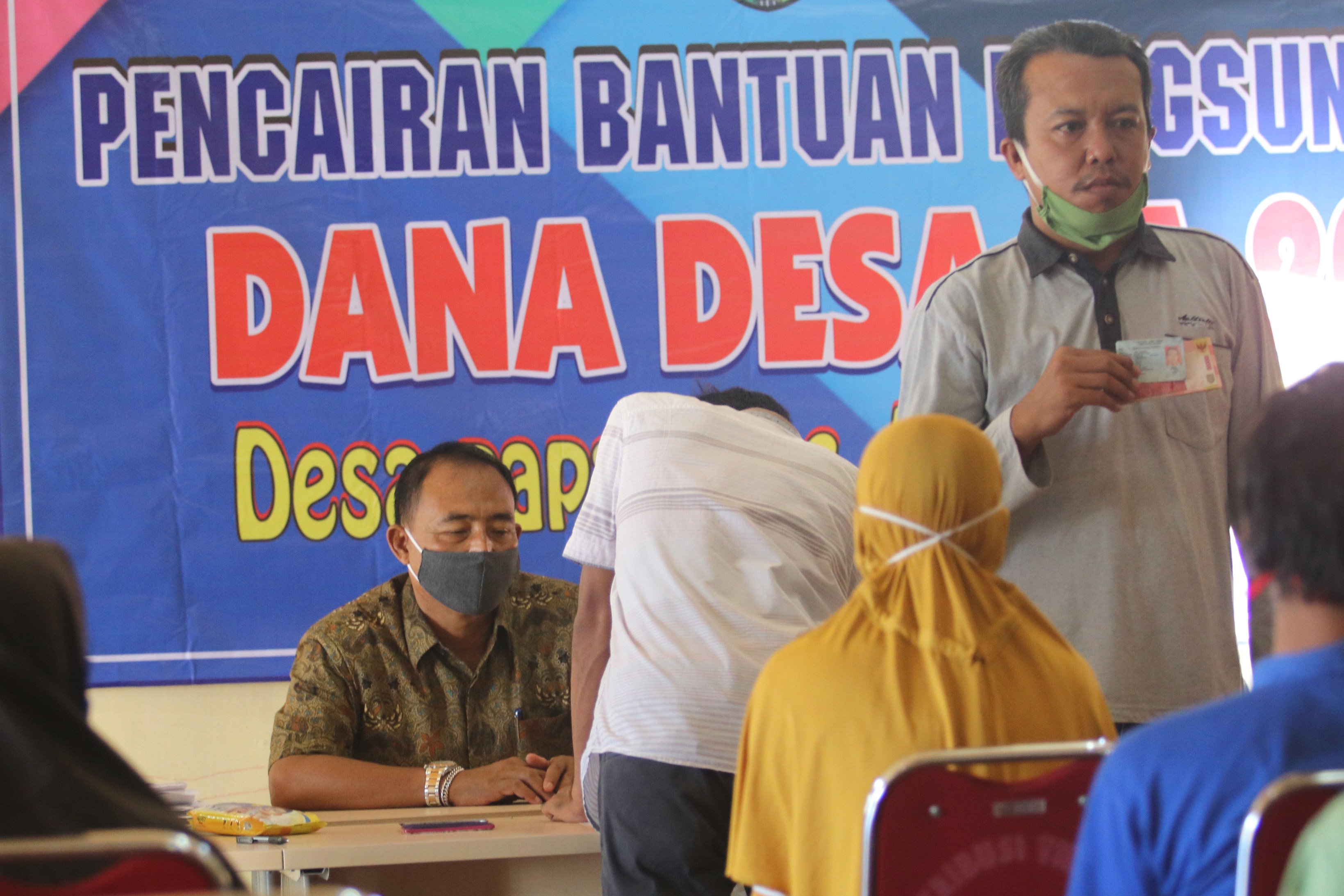 Warga kurang mampu terdampak pandemi covid-19 antre mengambil bansos Dana Desa di Desa Papar, Kediri, Jawa Timur, Rabu (20/5).