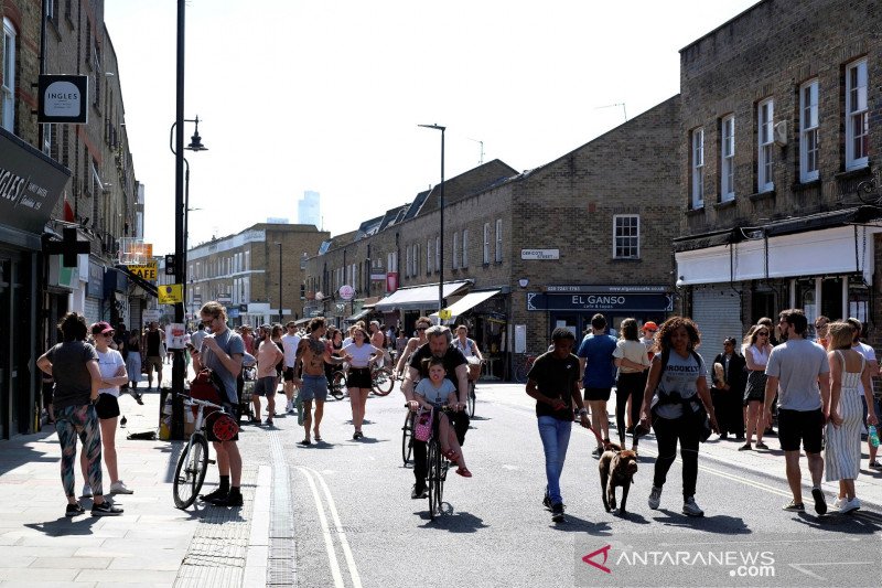 Warga berjalan dan bersepeda di sepanjang Broadway Market, di tengah pandemi virus korona (Covid-19), di London, Inggris, Sabtu (9/5).