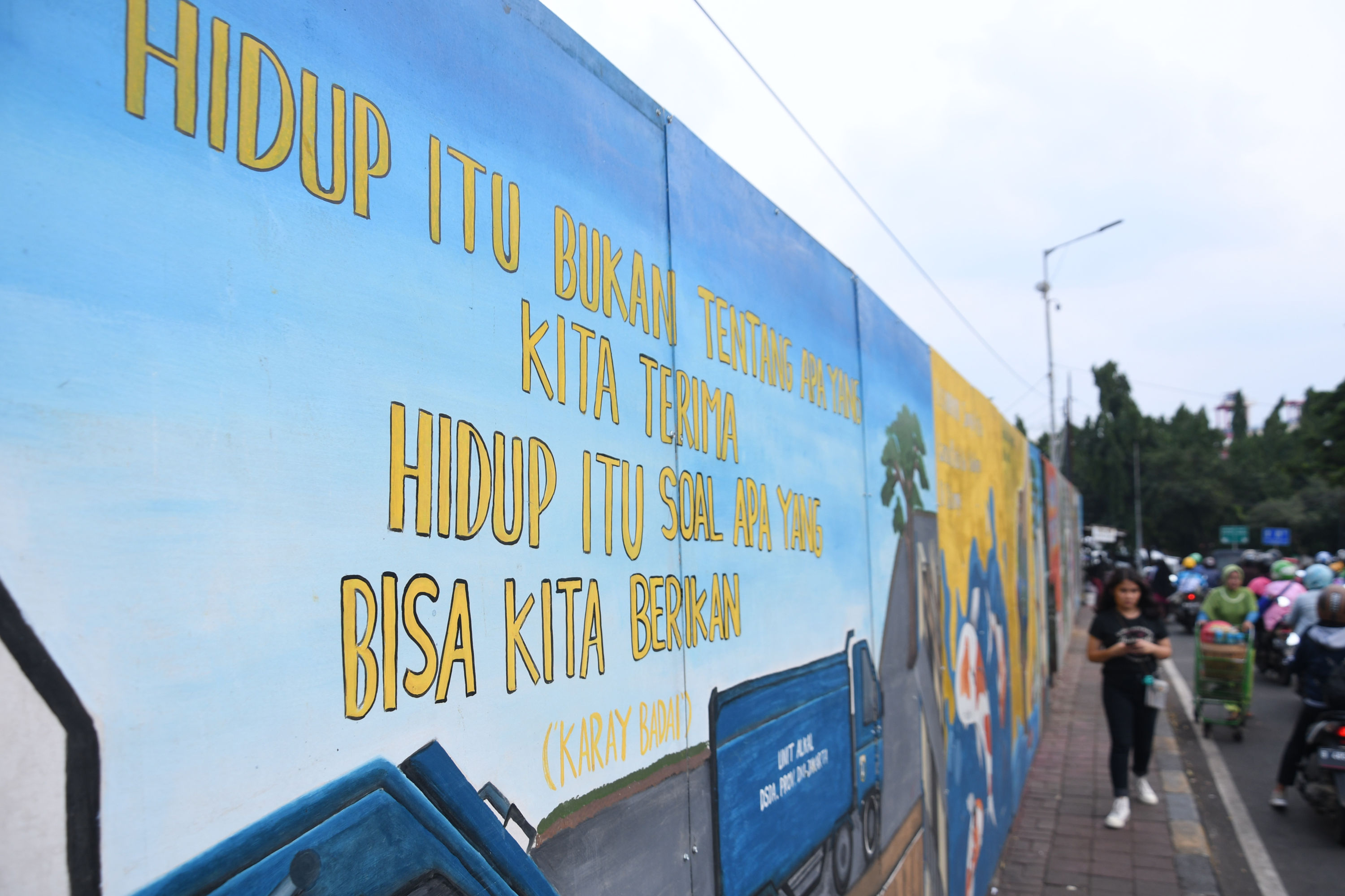 Warga melintas di depan mural yang berisi pesan ajakan untuk menjaga lingkungan di kawasan Jl. Tambak, Manggarai, Jakarta.