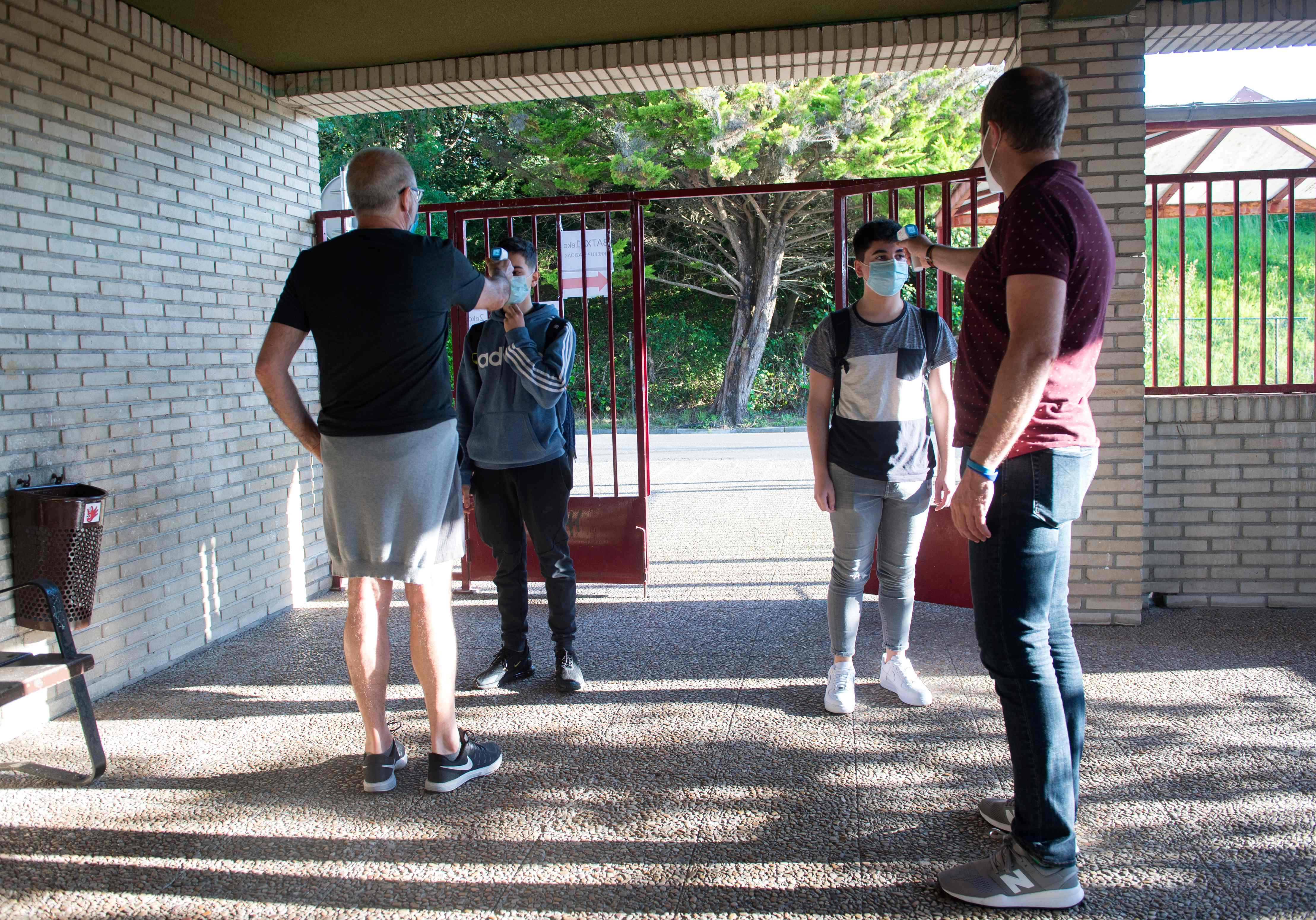 Pelajar diperiksa suhu tubuhnya saat tiba di Sekolah Axular Lizeoa, San Sebastian, Spanyol setelah sekolah mereka dibuka kembali.
