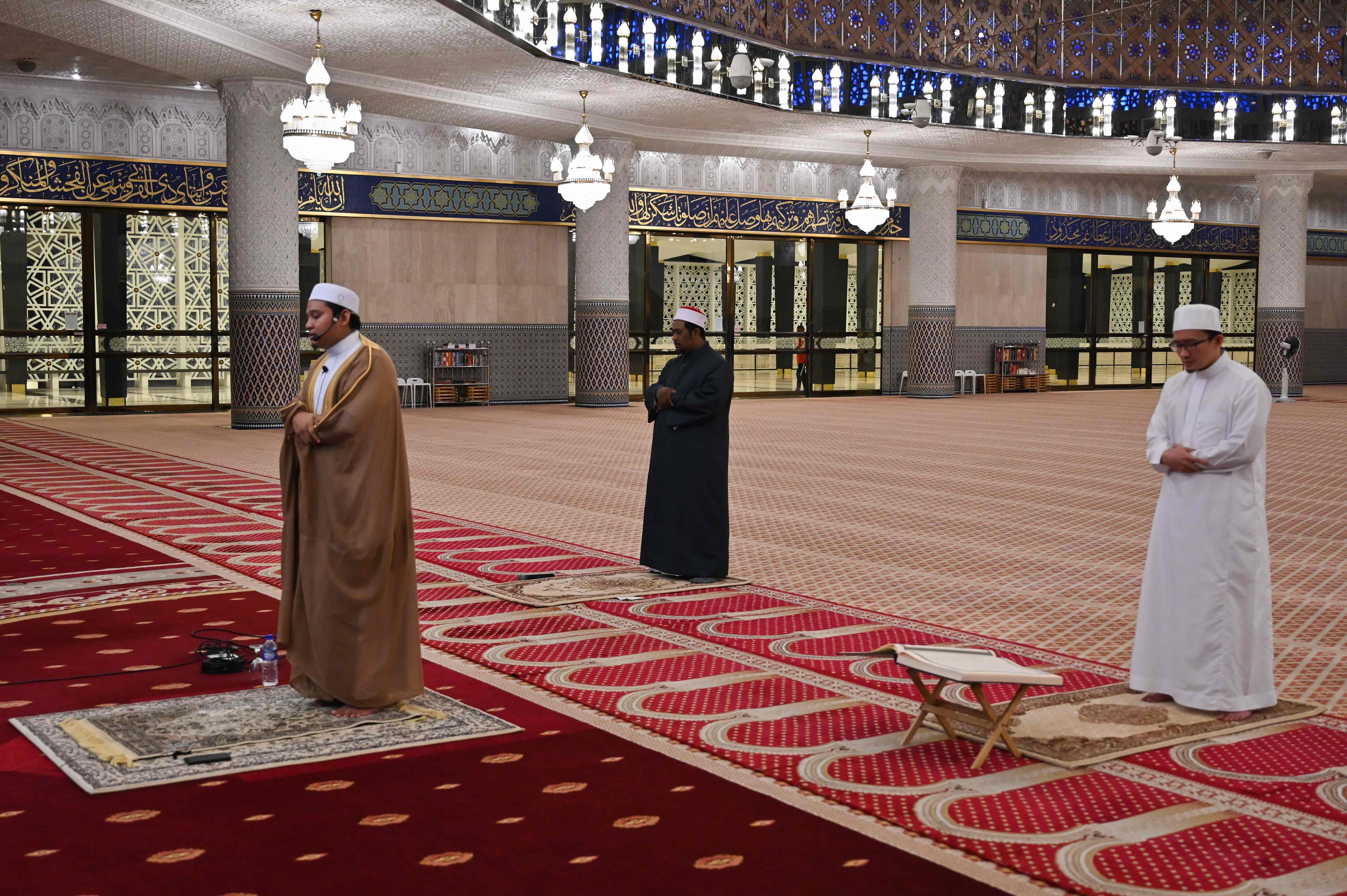 Ulama Muslim mempraktikkan jarak sosial sambil membaca doa malam terawih di siaran langsung Masjid Nasional di hari pertama Ramadan.