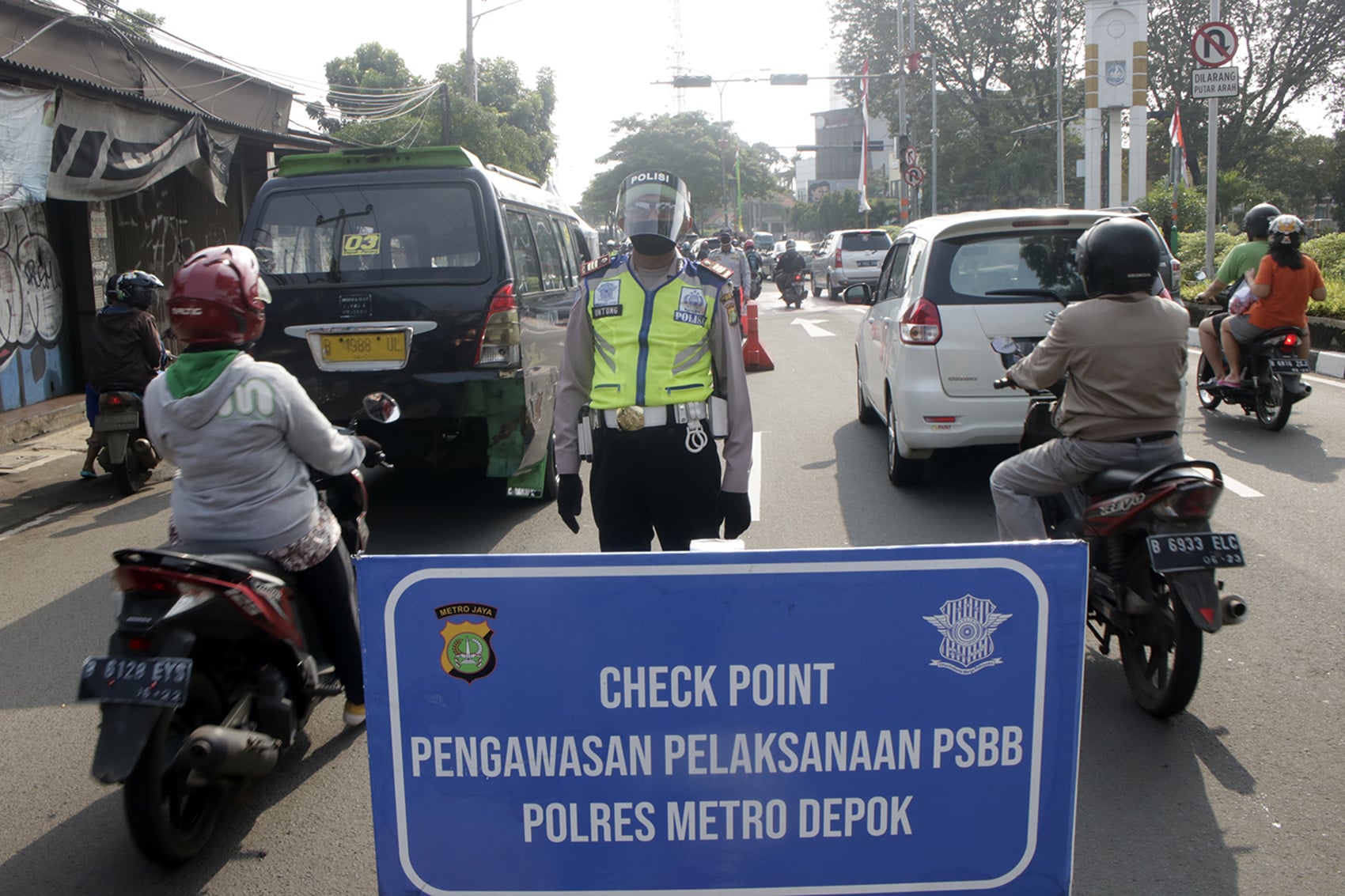Petugas menggunakan pelindung saat berjaga di check point PSBB Depok