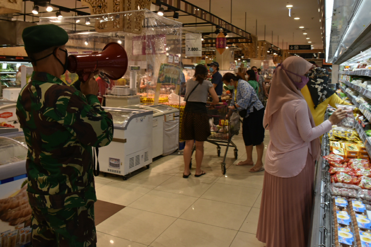  Petugas dari TNI berjaga dan menghimbau warga yang berbelanja untuj tetap menerapkan social distancing saat berbelanja.