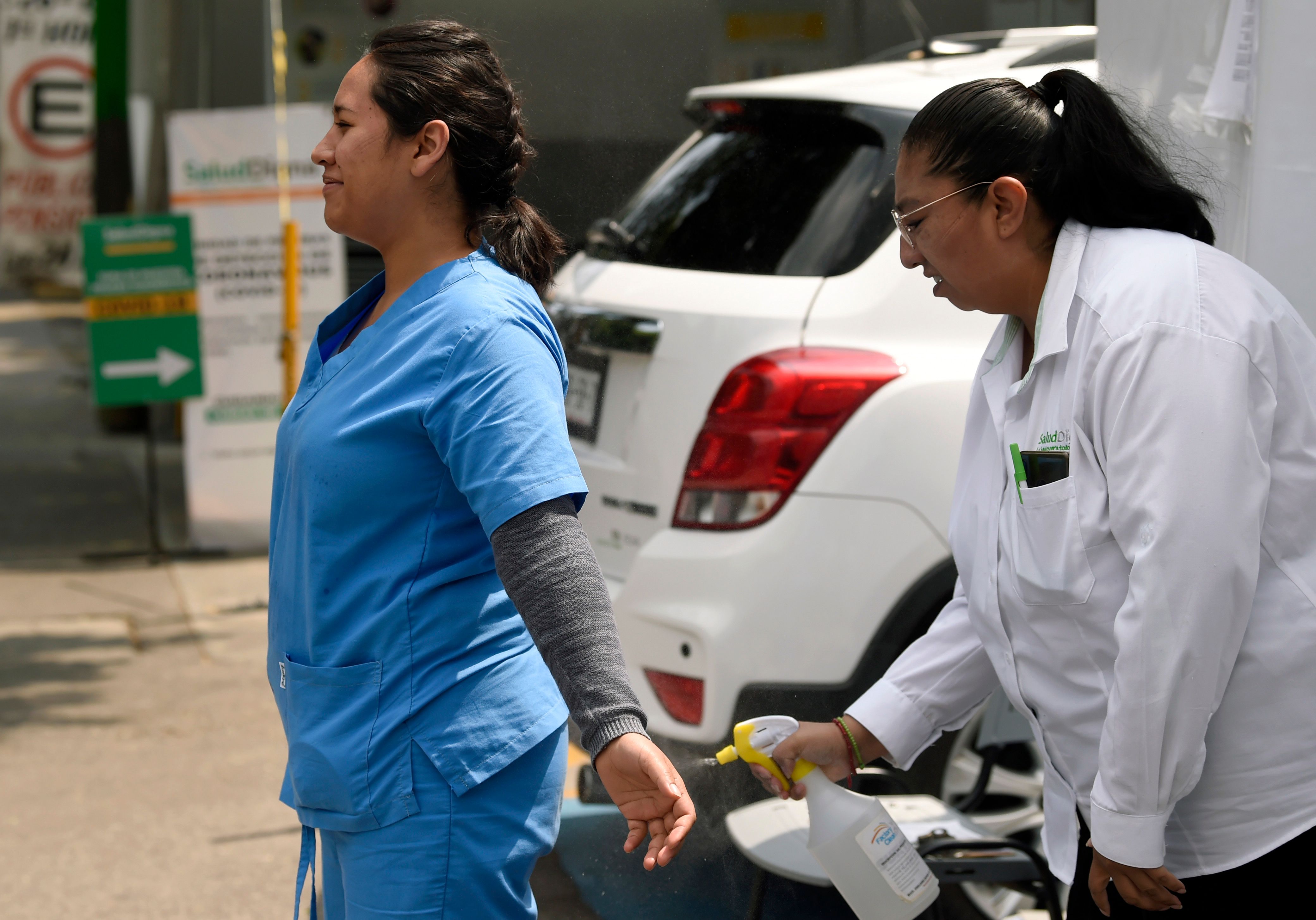 Petugas medis di RS Adolfo Lopez Mateos Kota Meksiko saling membantu menyemprotkan disinfektan .