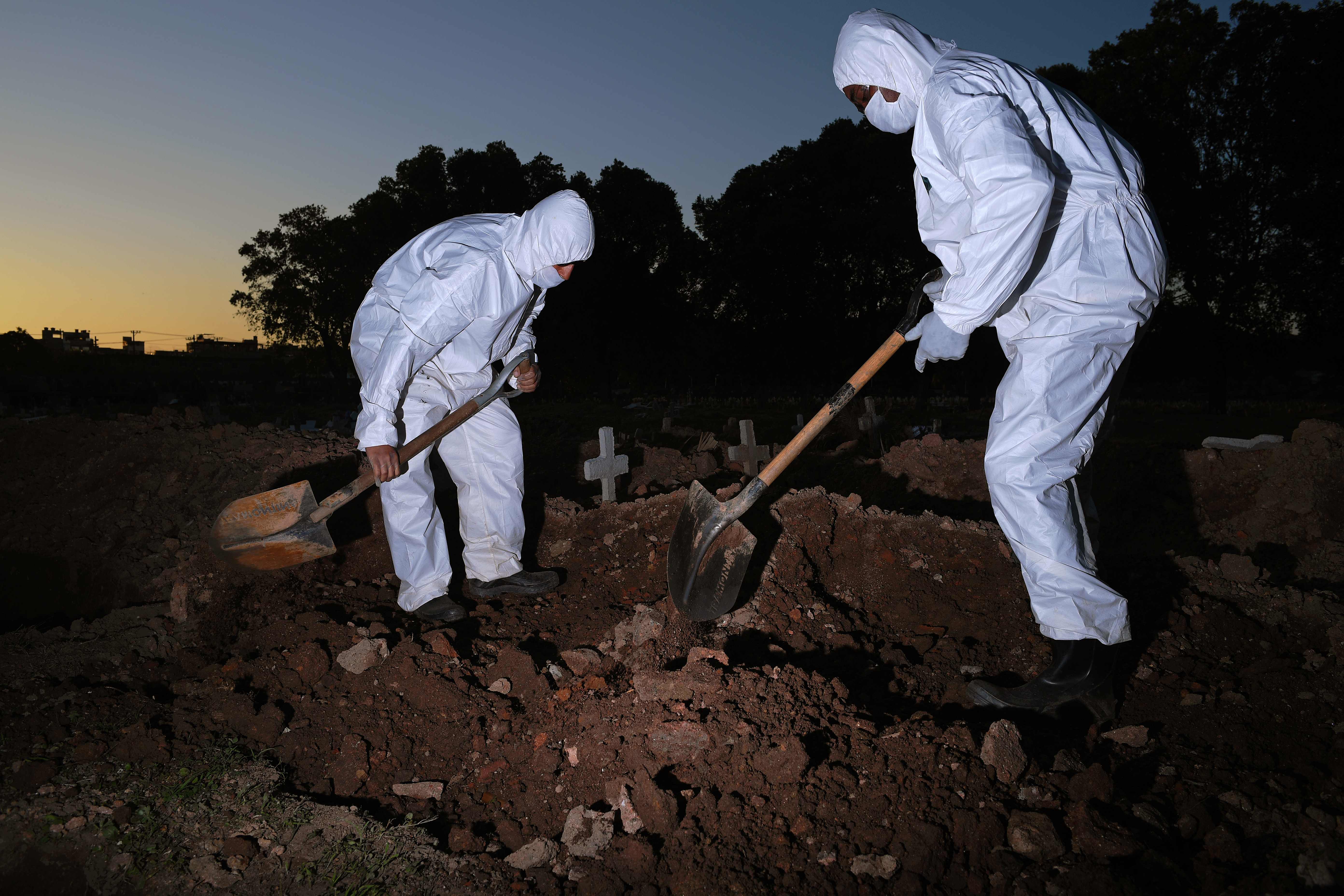 Petugas pemakaman mengenakan APD menguburkan jenazah korban covid-19 di taman makam San Fracisco Xavier di Rio de Janeiro, Brasil.