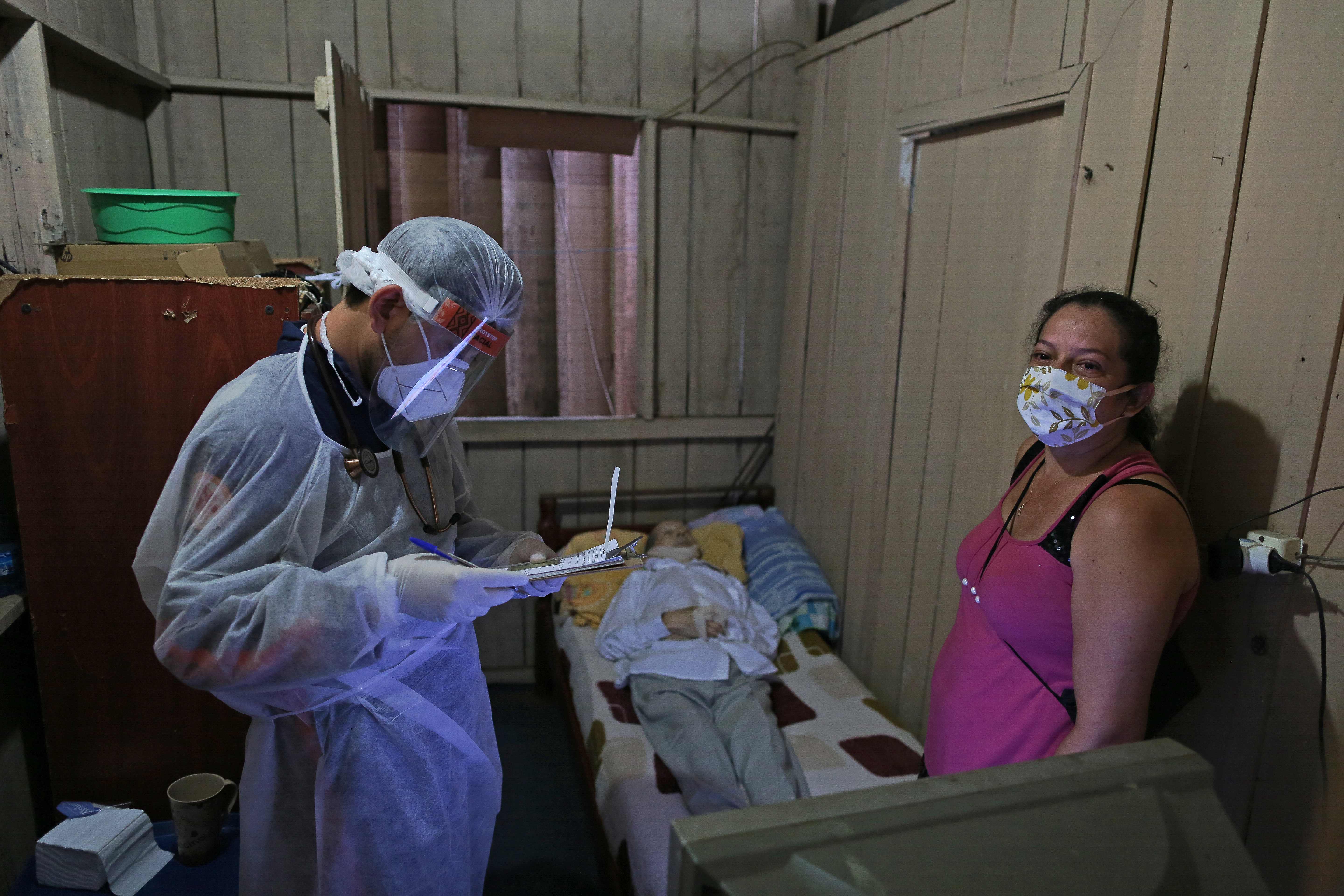 Petugas mengenakan APD menjemput jenazah korban covid-19 di rumahnya di Manaus, Brasil.