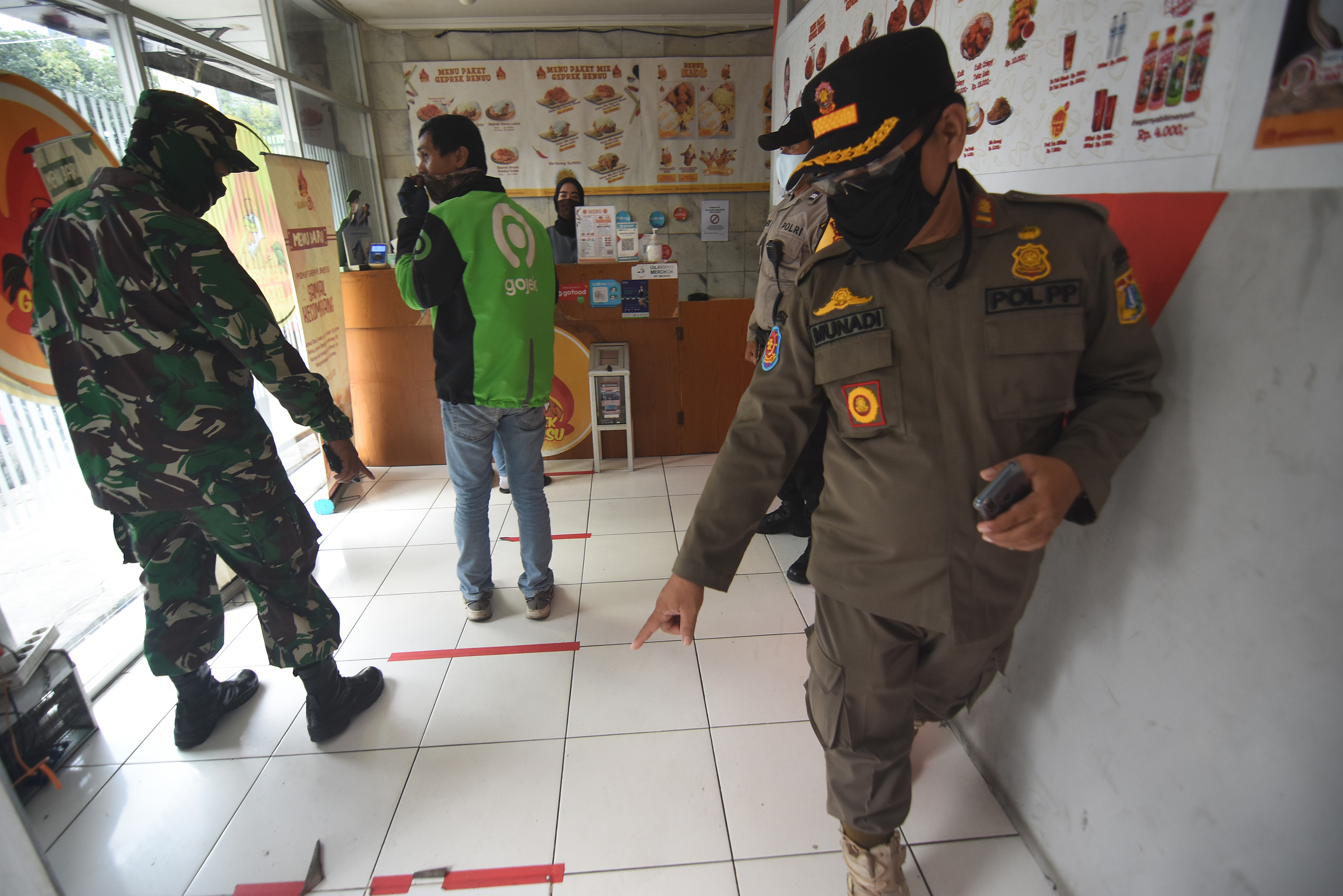 Petugas gabungan memberi imbauan untuk menjaga jarak antrean saat patroli penegakan aturan PSBB di restoran Kalibata Jakarta Selatan.