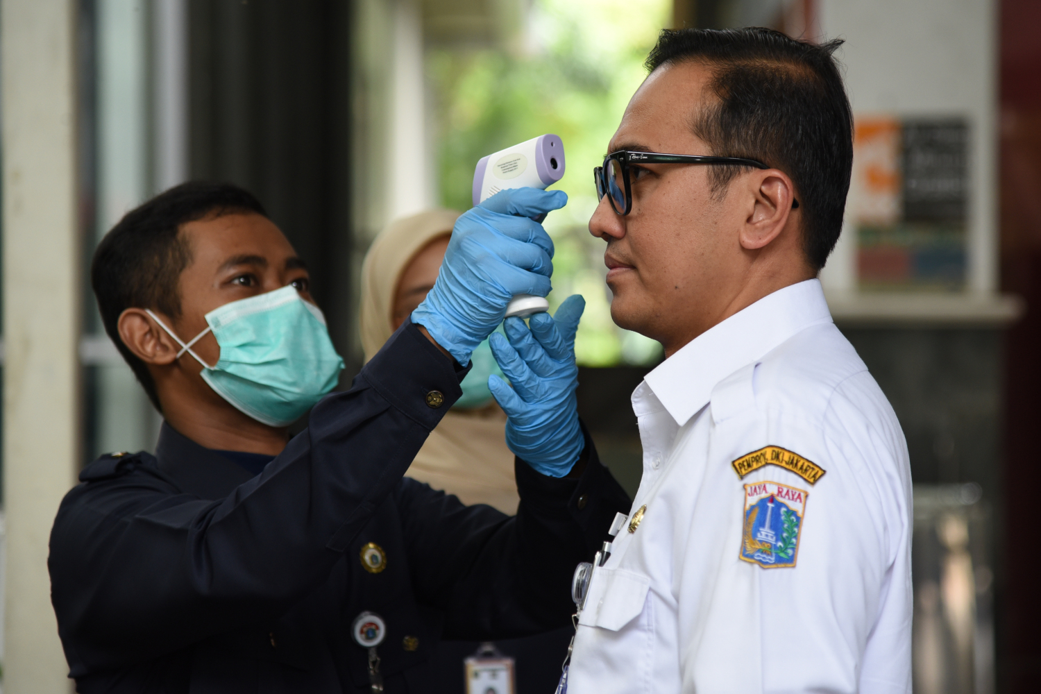 Petugas melakukan pengecekan suhu tubuh bagi para aparatur sipil negara (ASN) maupun warga yang berkunjung ke Gedung Balai Kota, Jakarta