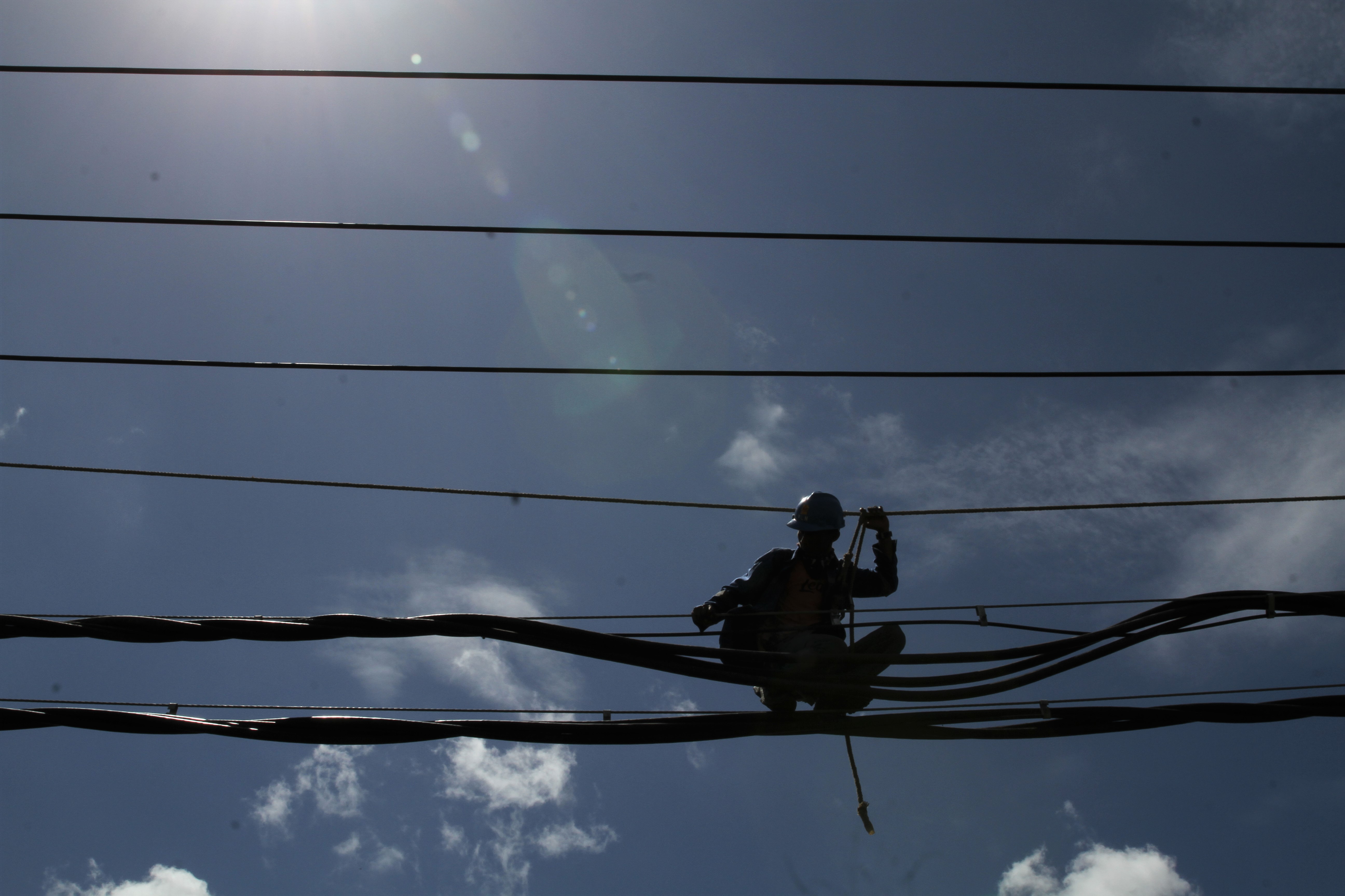 Pekerja memasang kabel empetik milik PT PLN Persero di jalur aliran penghubung tiga kabupaten, Kendari, Sulawesi Tenggara, Minggu (10/5).