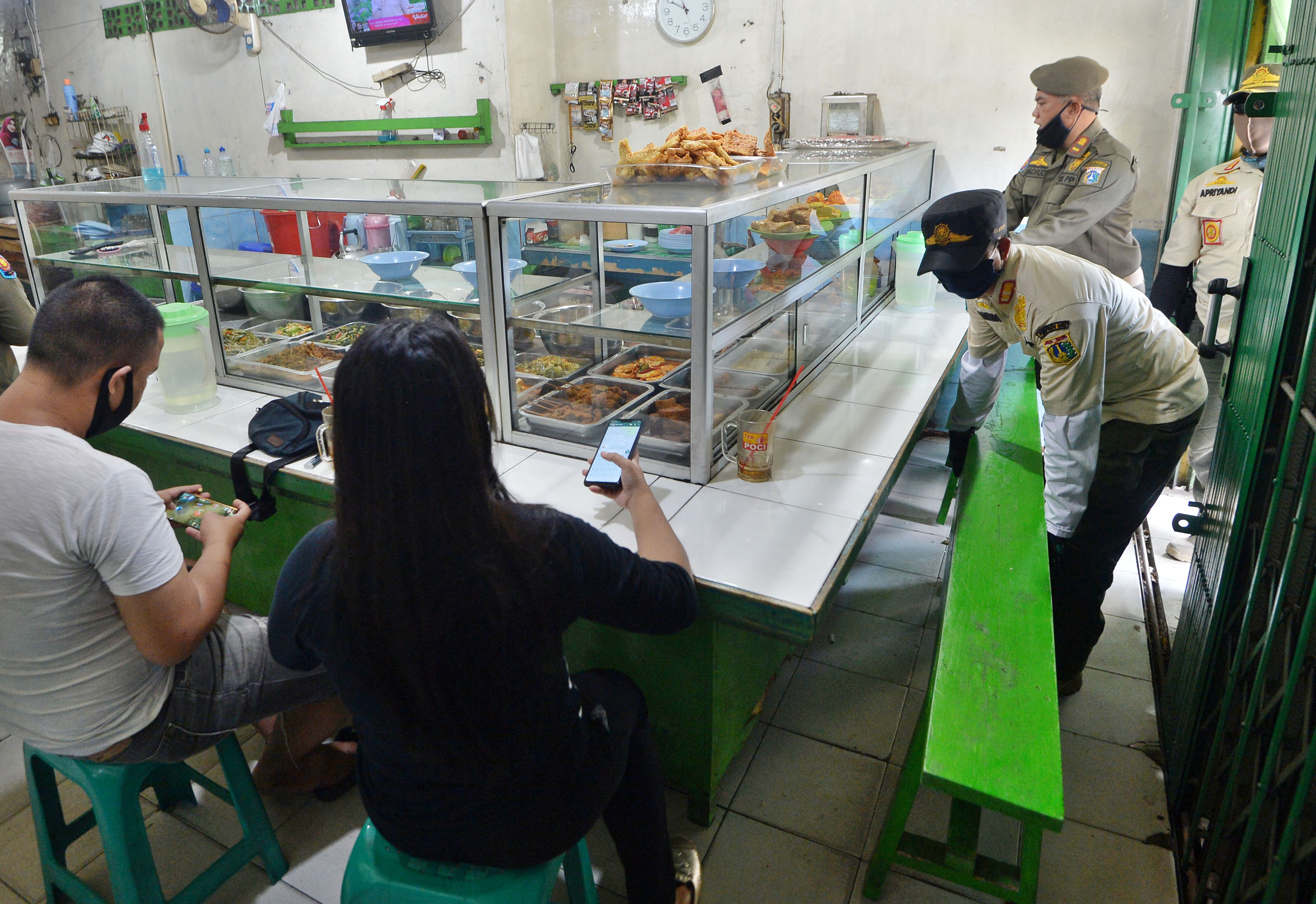 Petugas Satpol PP menertibkan warung makan yang melanggar aturan PSBB di Cililitan, Jakarta.