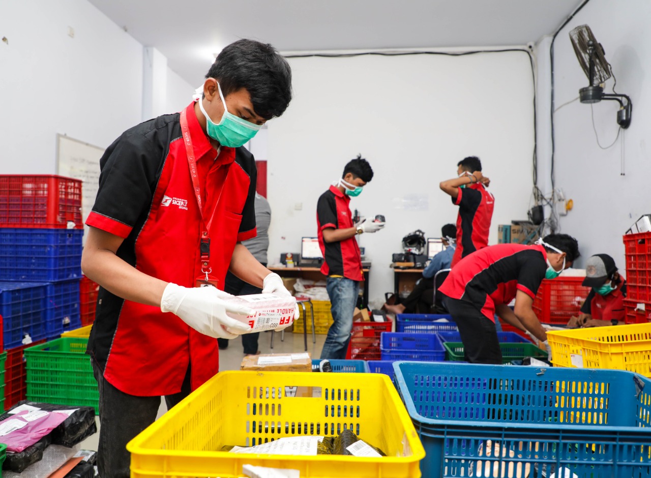 Petugas layanan ekspedisi SiCepat memilah barang yang akan dikirim ke konsumem