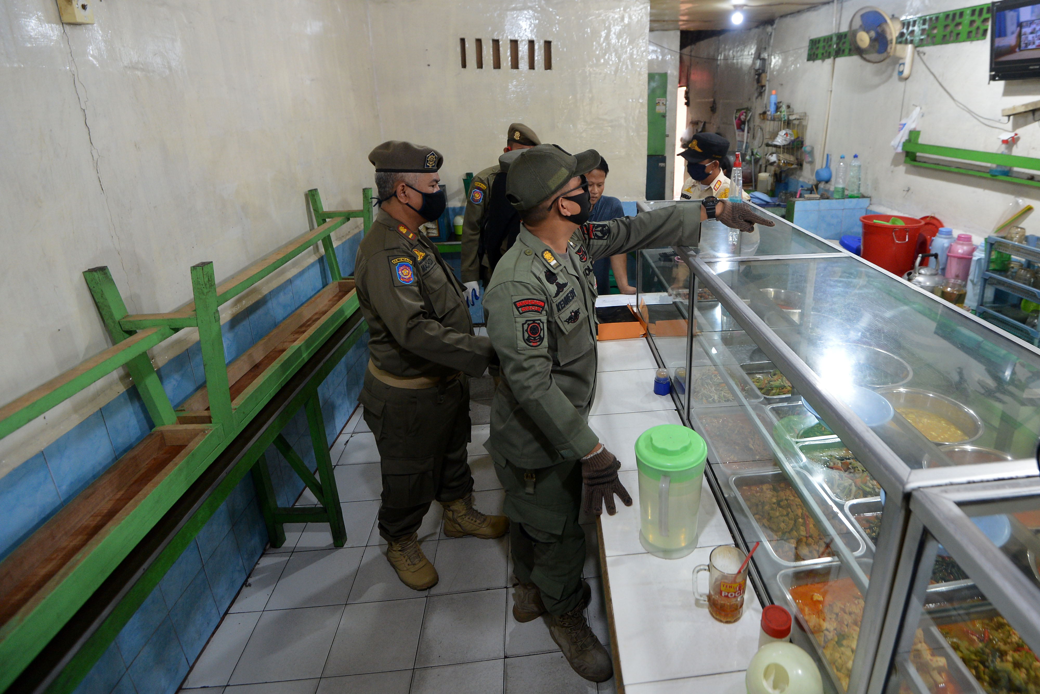 Petugas Satpol PP menertibkan warung makan yang melanggar aturan PSBB di Cililitan, Jakarta.