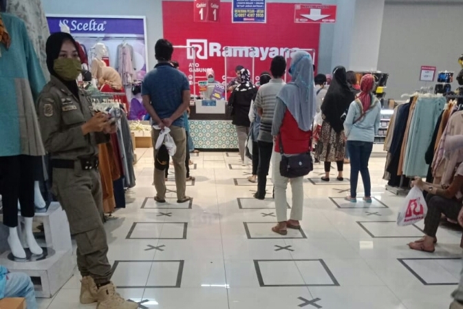 Satpol PP mengatur antrean warga untuk menanggulangi penyebaran virus korona.