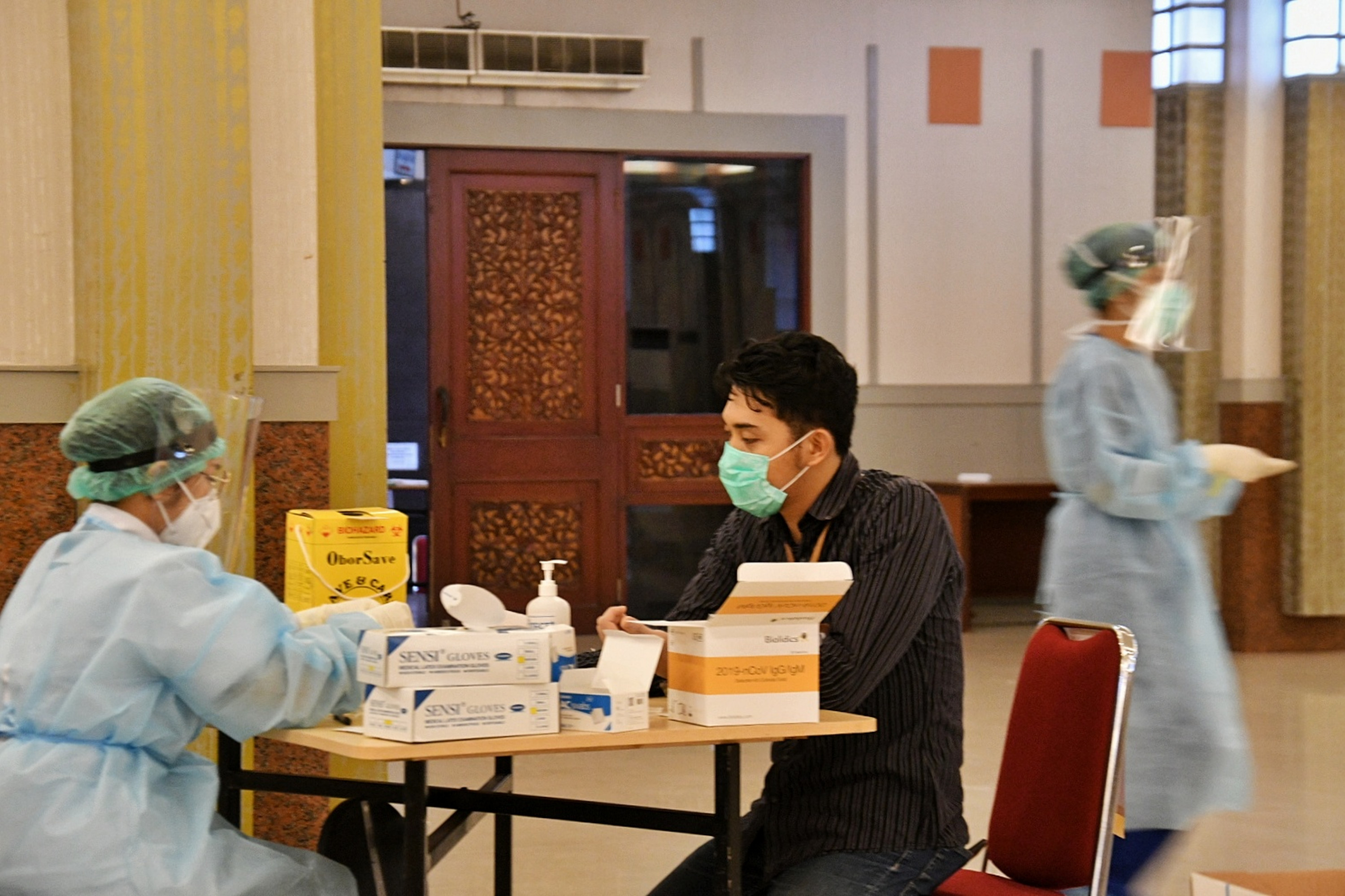 Petugas sedang melakukan rapid test kepada seorang pekerja. 