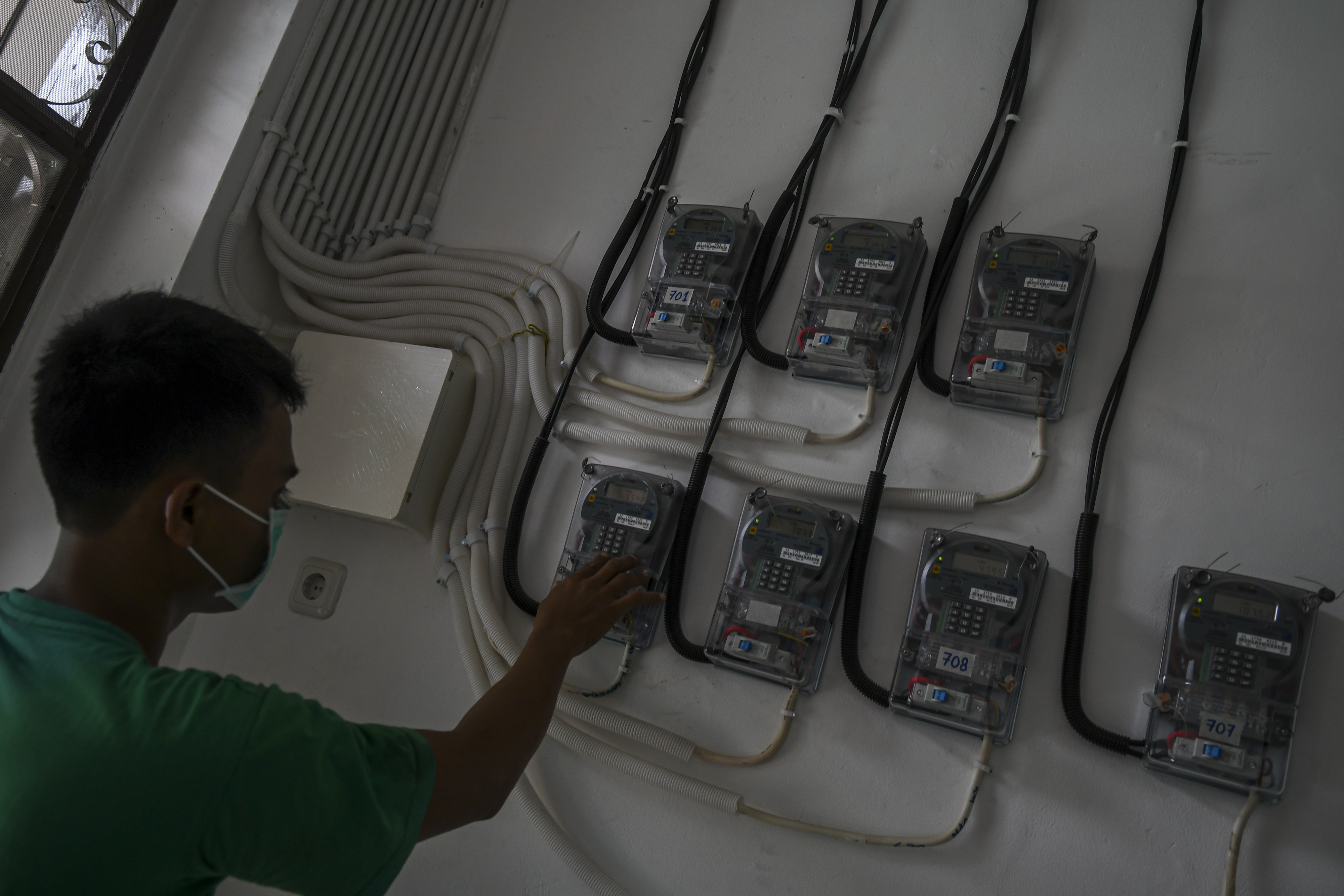 Warga memasukkan pulsa listrik PLN melalu meteran dengan token