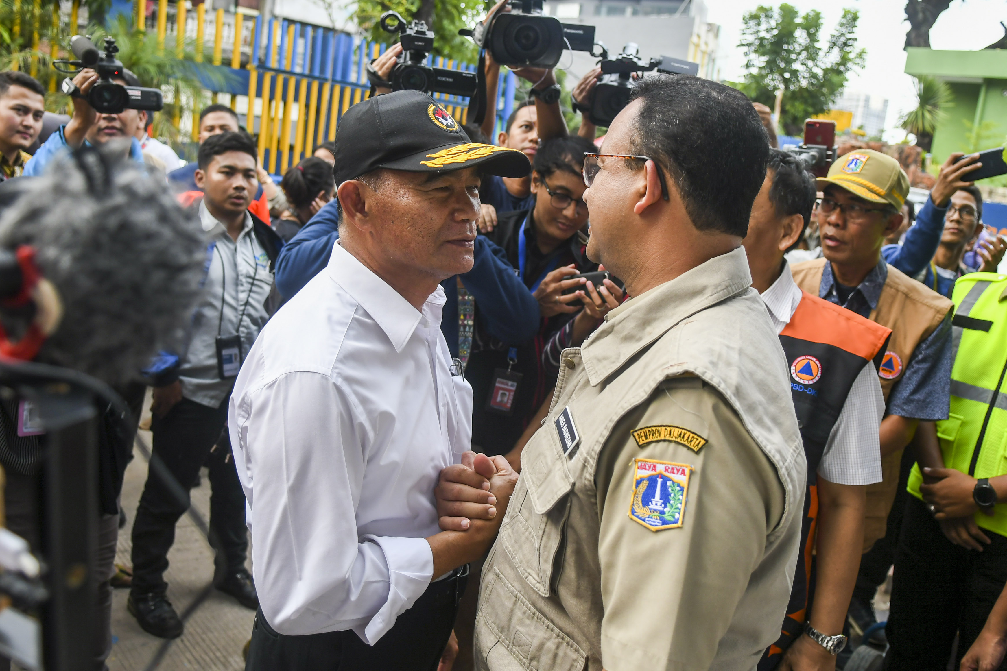 Menko PMK Muhadjir Effendy menjabat tangan Gubernur DKI Anies Baswedan saat meninjau pintu air Manggarai.