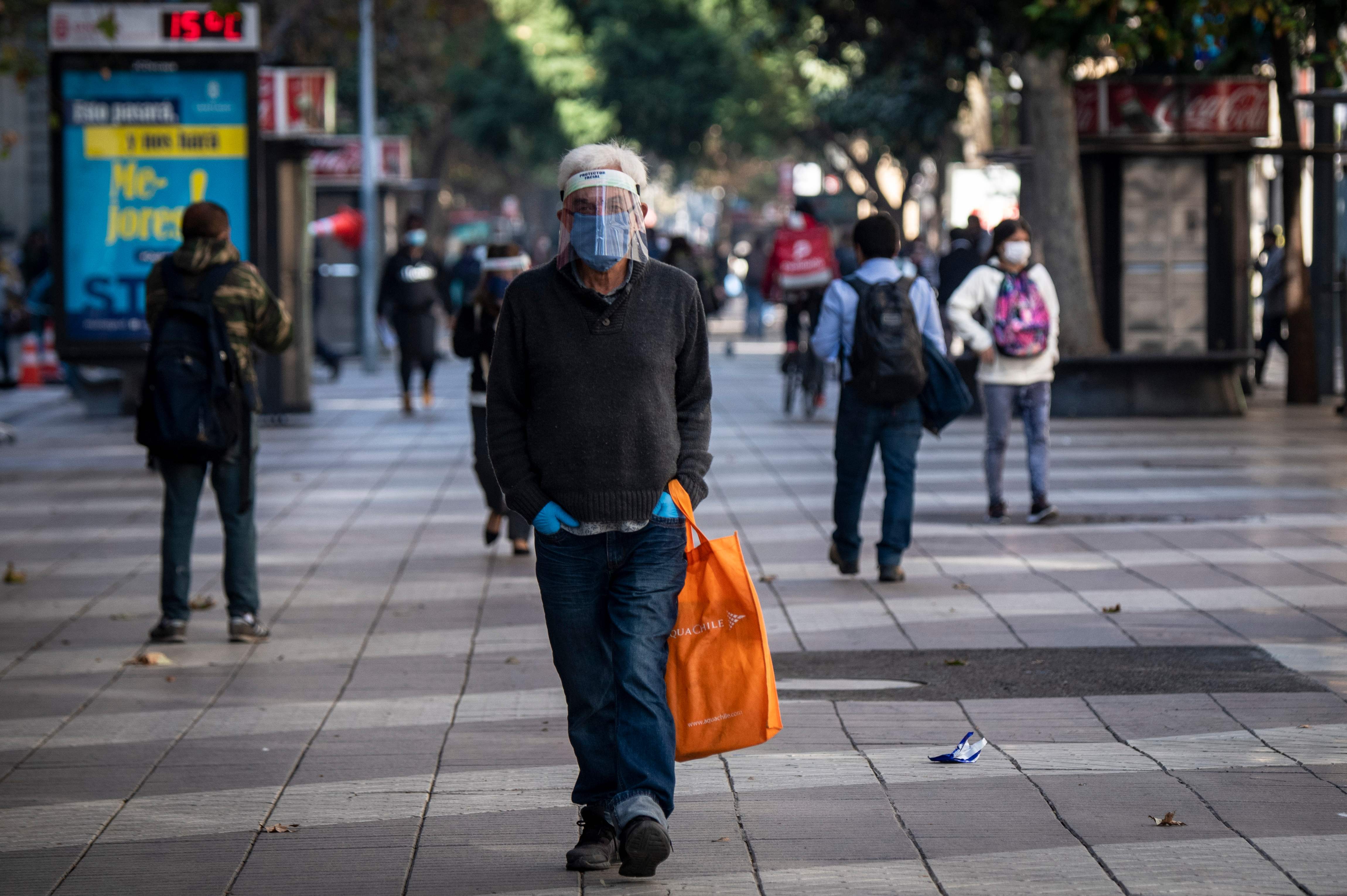 Warga mengenakan masker dan face mask berjalan di ibu kota Cile, Santiago.