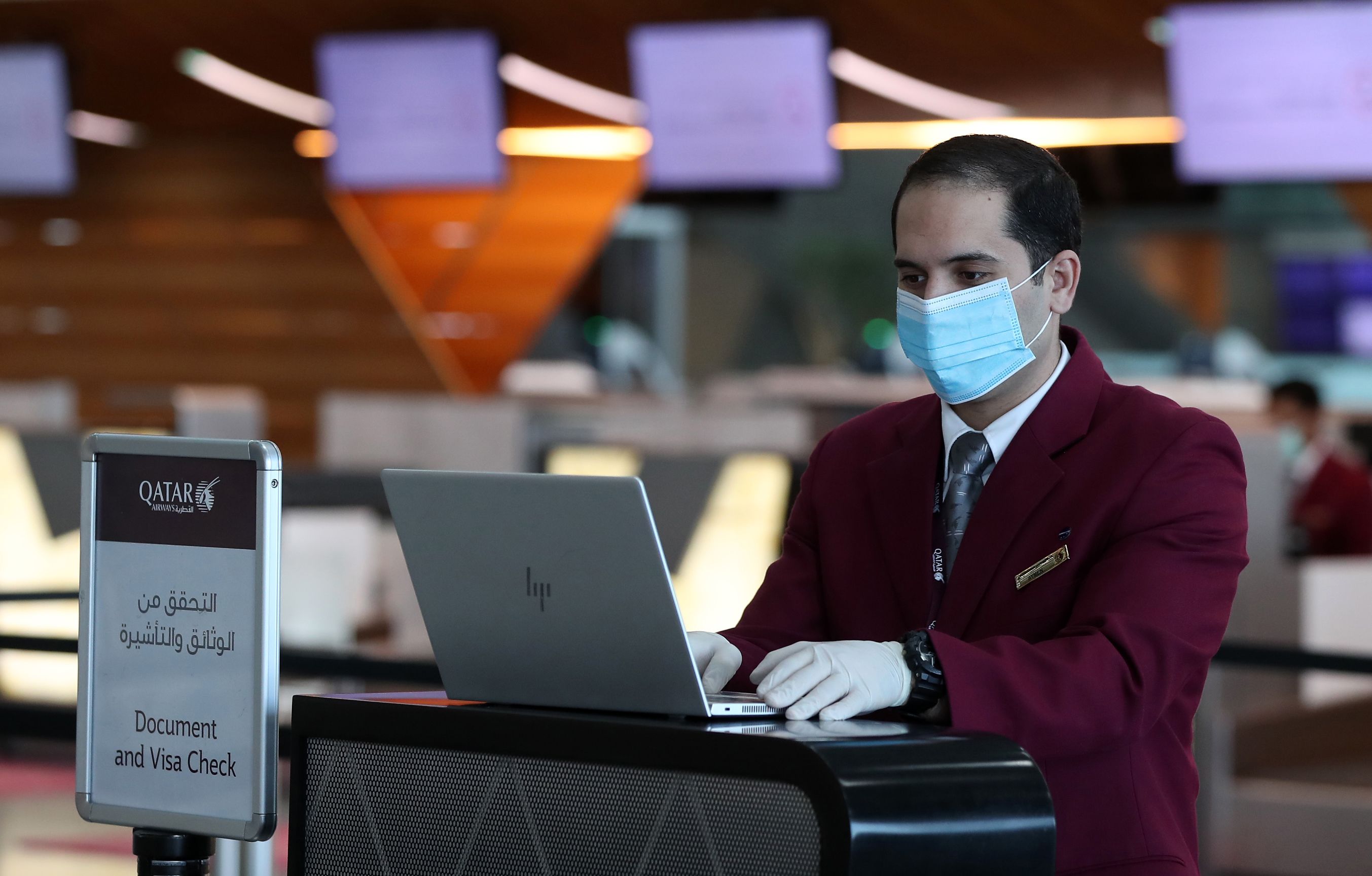 Petugas di Bandara Internasional Hamad di Doha, Qatar mengenakan masker dan sarung tangan.