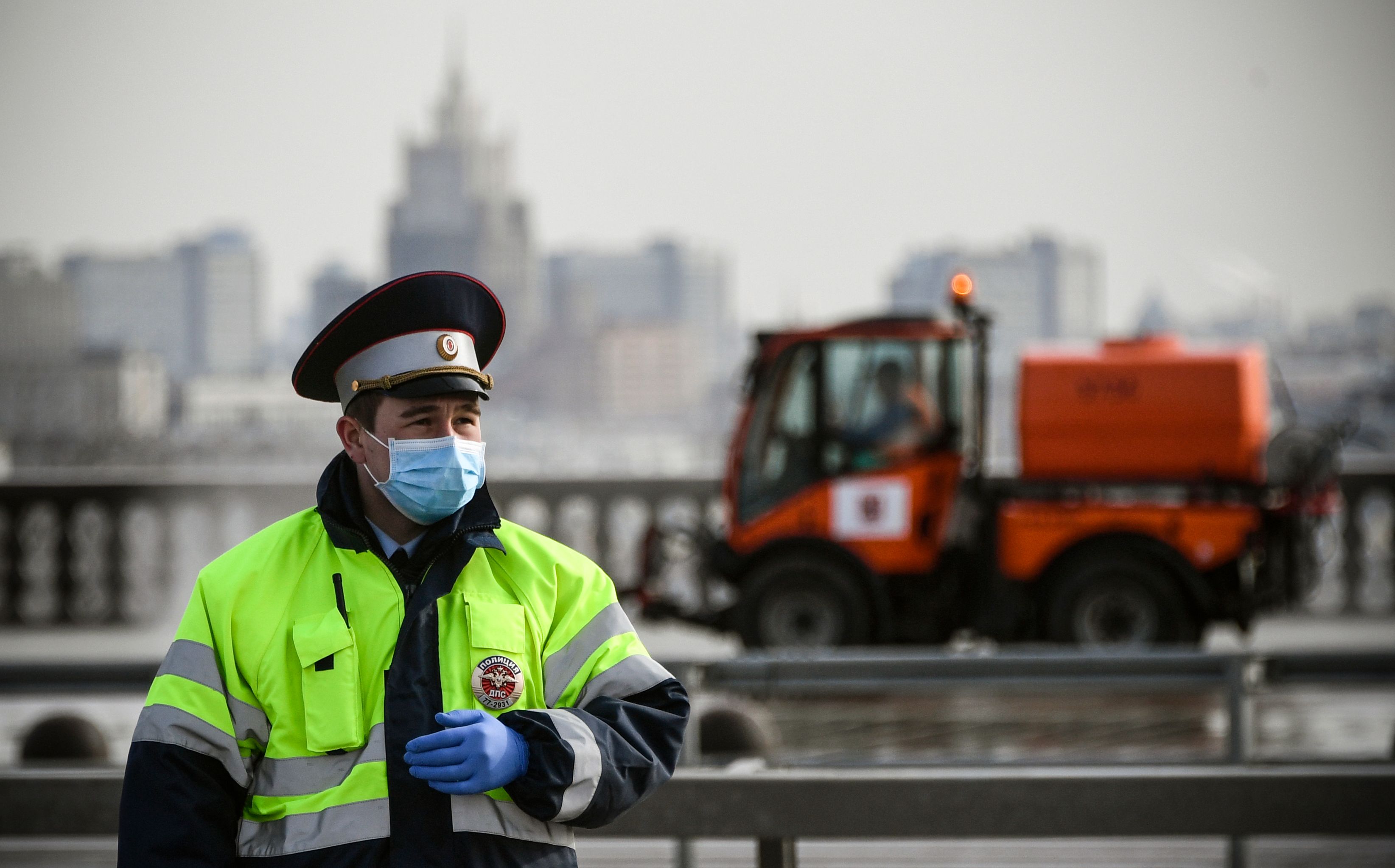  Polisi lalu lintas Rusia mengenakan masker wajah dan sarung tangan di depan kendaraan kota membersihkan jalan di MOskow (24/4)