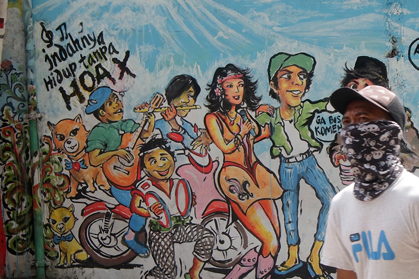 Warga melintasi mural di Karet, Depok, Jawa Barat.