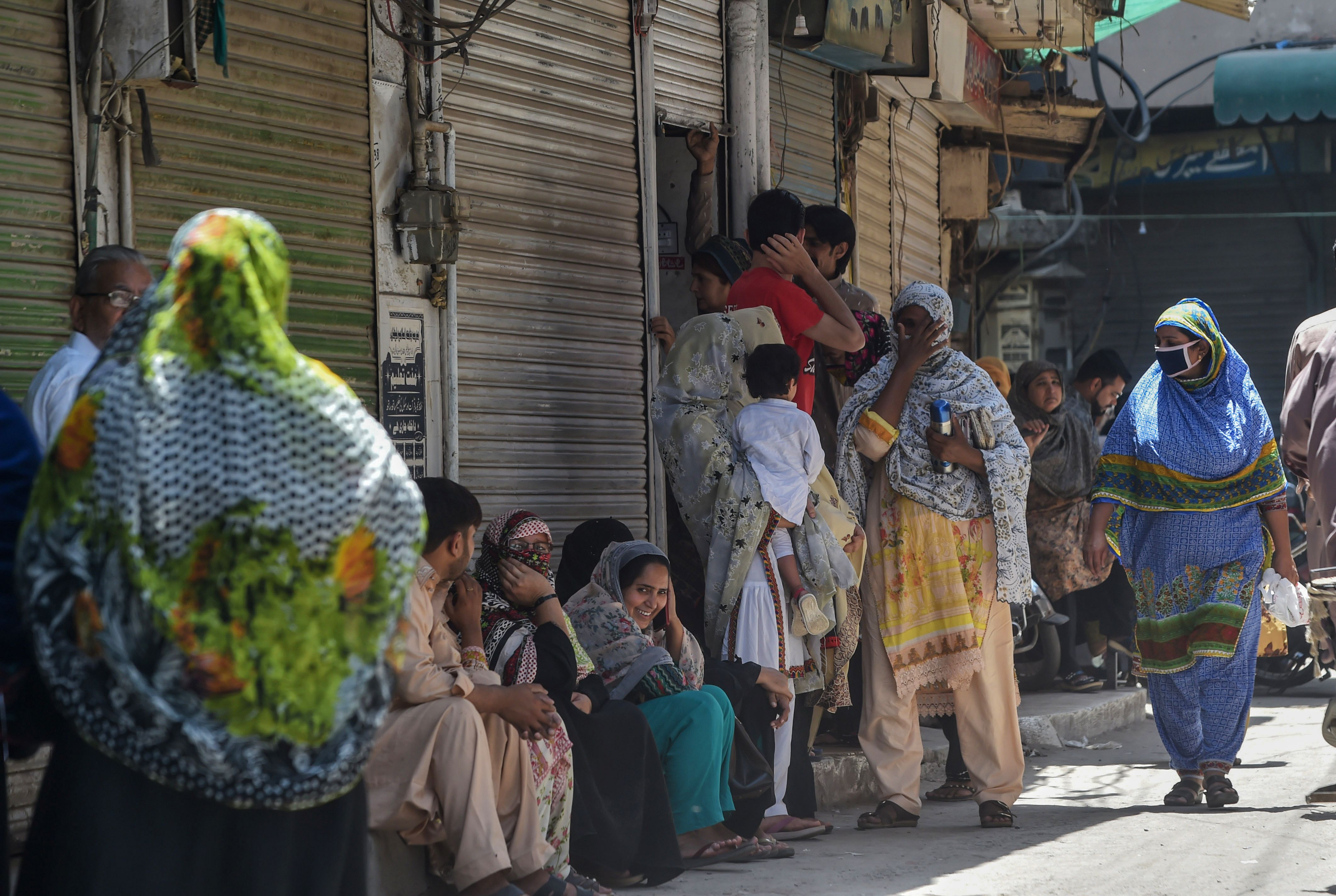 Warga Pakistan menunggu pertokoan buka setelah pemerintah melonggarkan lockdown.
