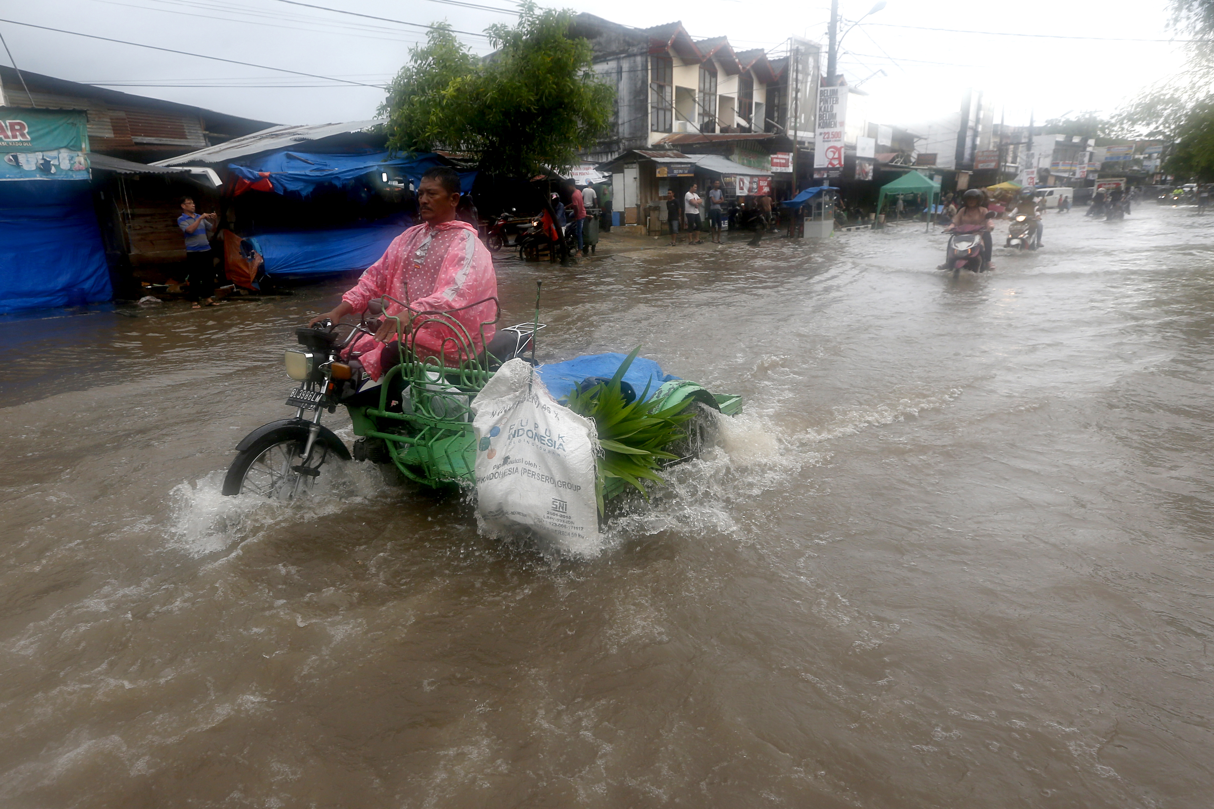 Warga melintas di jalan yang tergenang banjir di Desa Neusu, Banda Aceh, Aceh, Jumat (8/5/2020). 