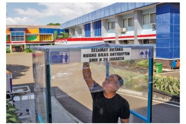 Petugas keamanan memeriksa bilik disinfeksi di pintu masuk SMKN 26 Rawamangun, Jakarta Timur, kemarin.