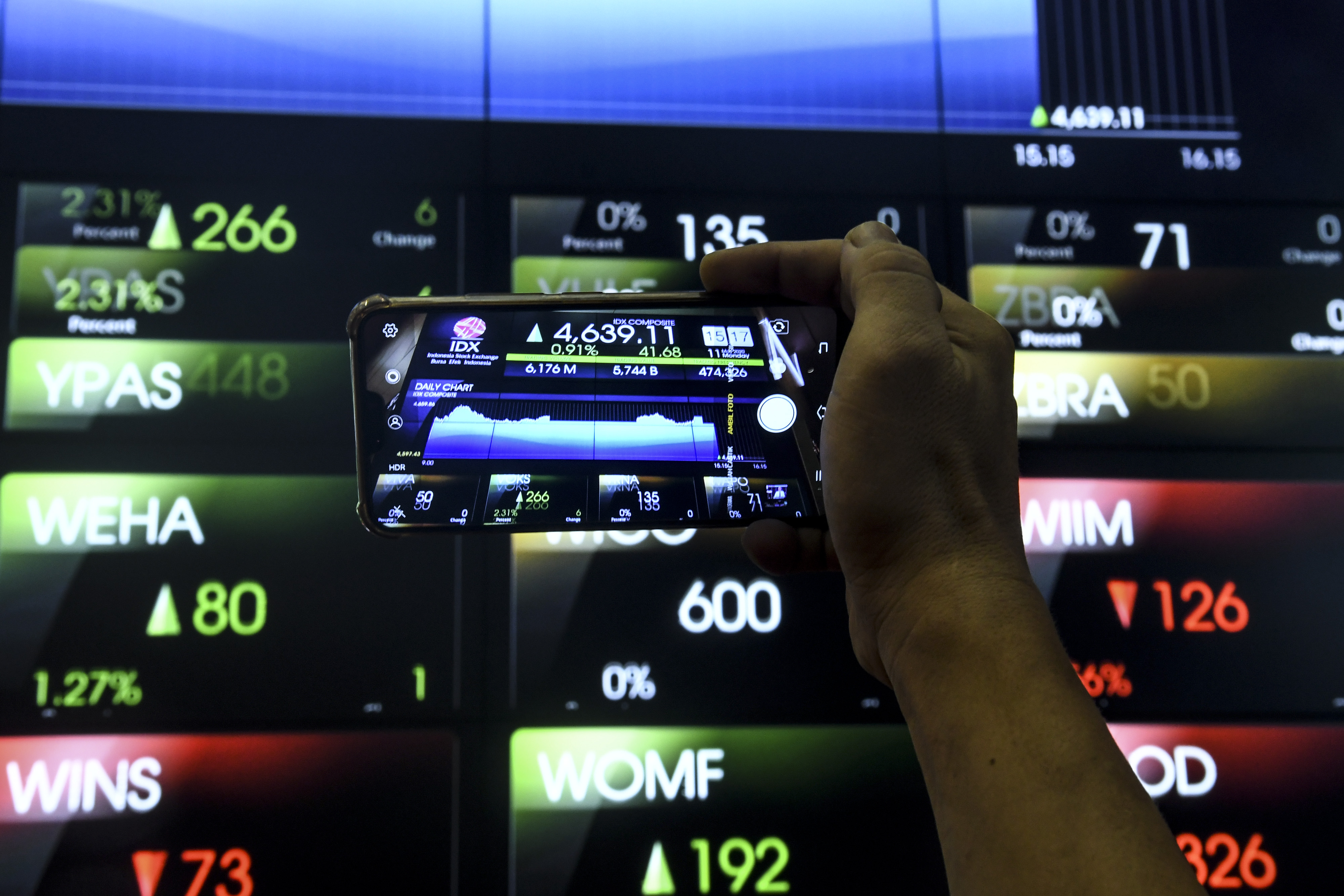 Pekerja mengambil gambar pergerakan Indek Harga Saham Gabungan (IHSG) dengan ponselnya di Bursa Efek Indonesia, Jakarta, Senin (11/5/2020).