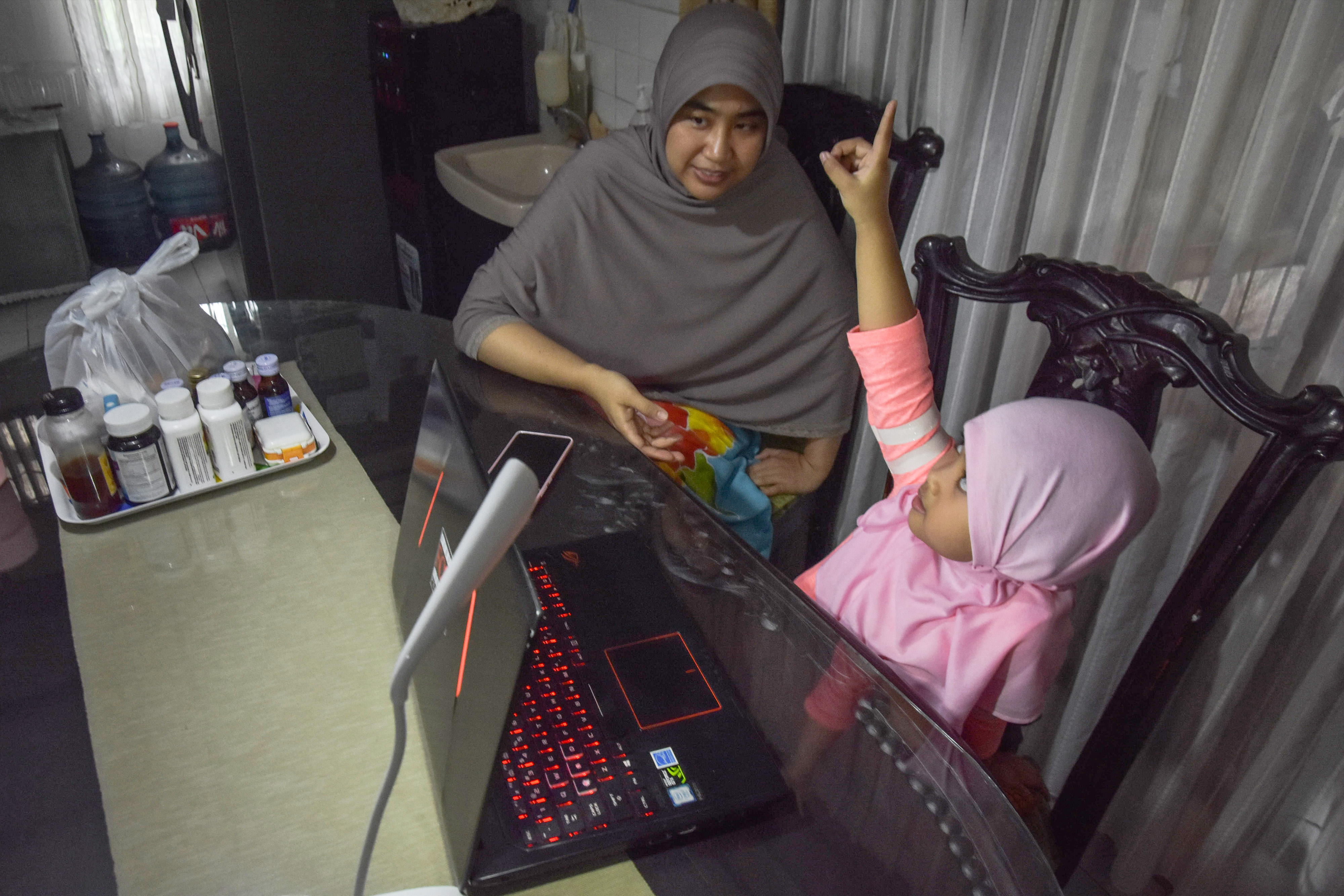 Seorang ibu mendampingi anaknya belajar dengan metode dalam jaringan atau secara online.