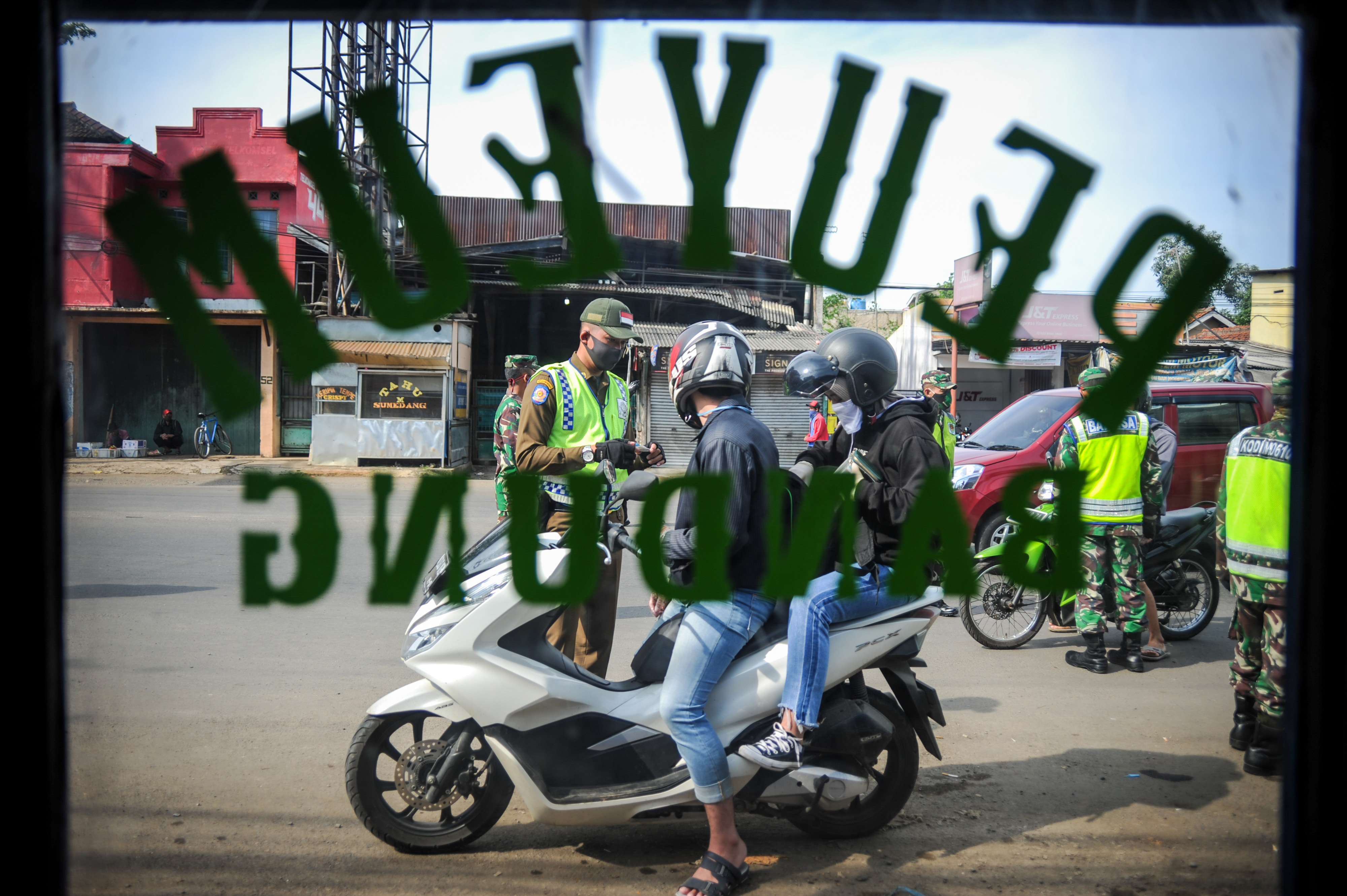  Petugas memberhentikan kendaraan bermotor di titik pemeriksaan Pembatasan Sosial Berskala Besar (PSBB) di Jatinangor.