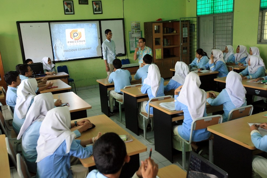 Guru sedang mengajar di muka kelas, 