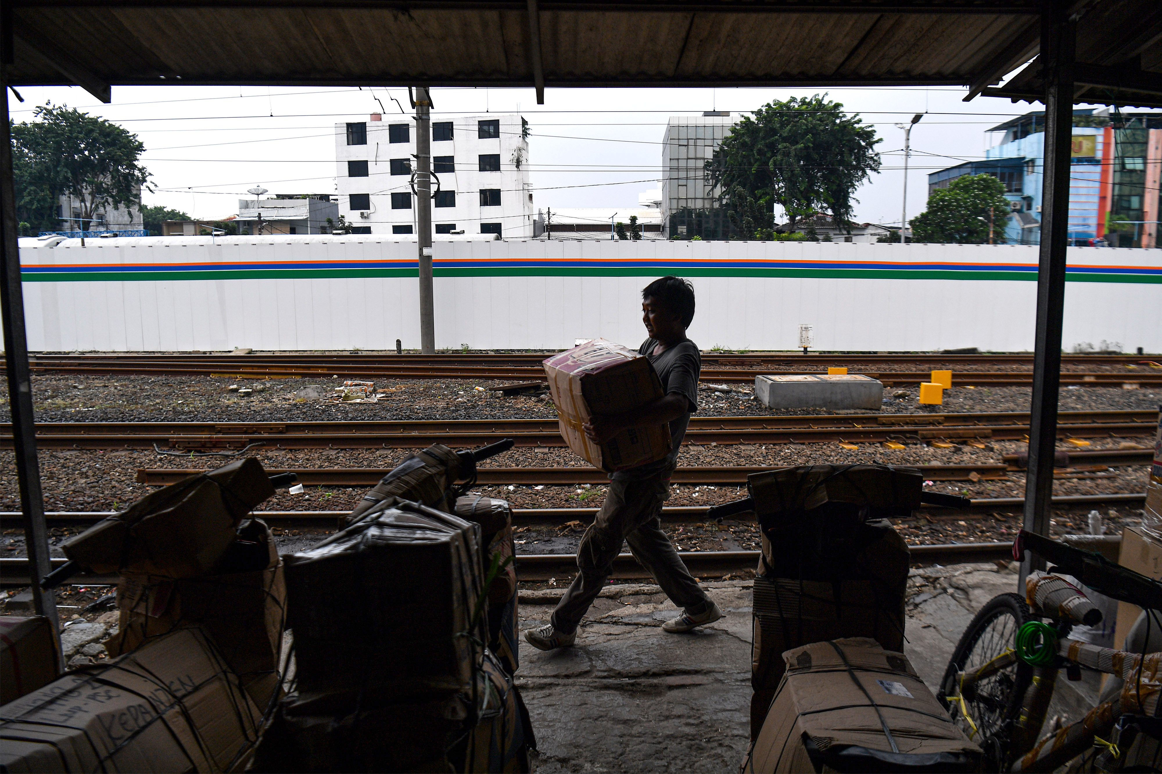 Pekerja membawa barang yang akan dikirim melalui kereta api di Stasiun Pasar Senen, Jakarta Pusat.