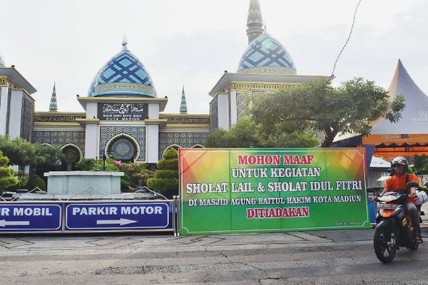 Papan pengumuman yang berisi peniadaan salat Idul Fitri dipasang di halaman Masjid Agung Baitul Hakim Kota Madiun, Jawa Timur, Jumat (15/5).