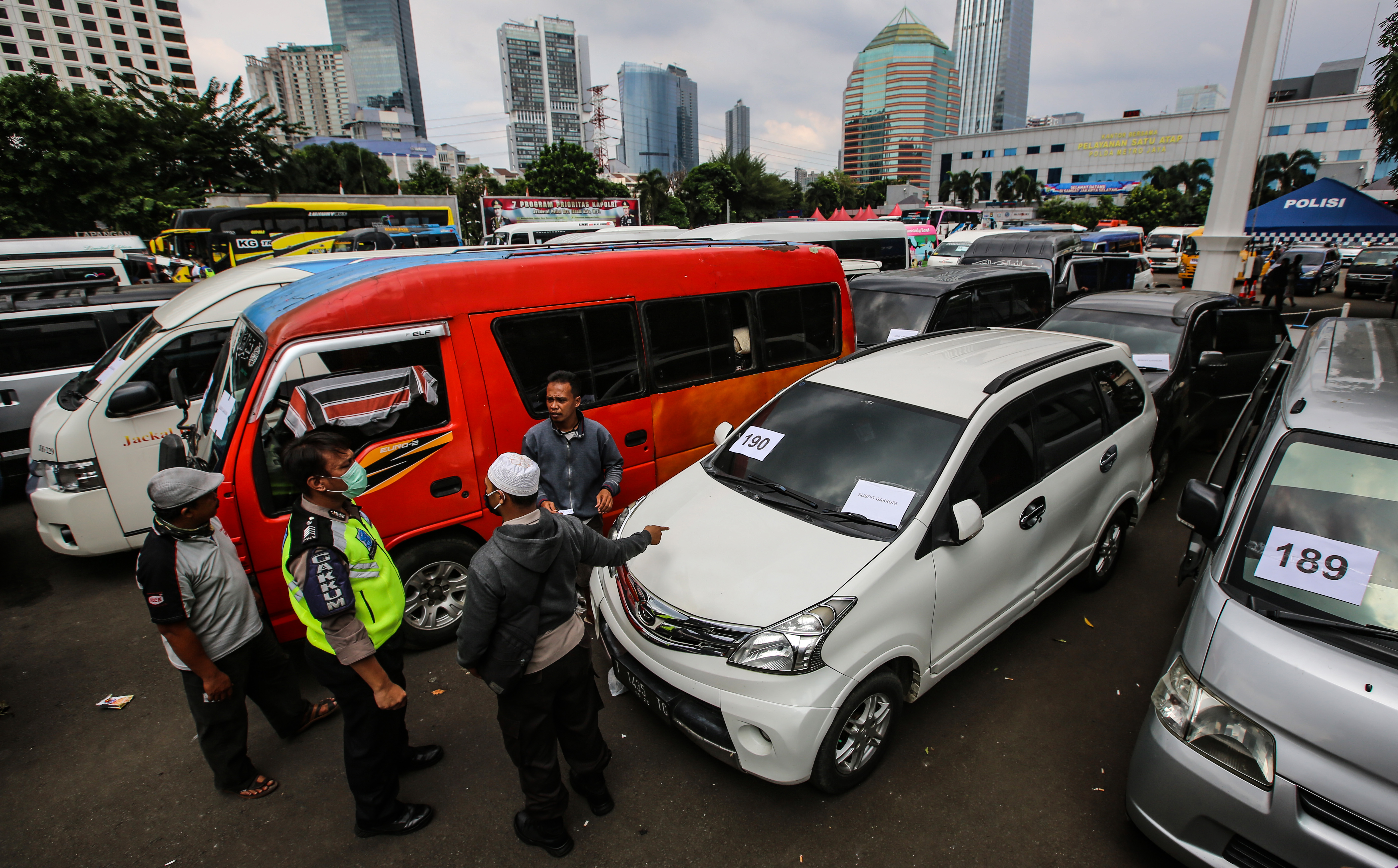 Awak travel yang terjaring operasi penyekatan menunggu proses tindakan di area penyitaan barang bukti di Polda Metro Jaya, Jakarta