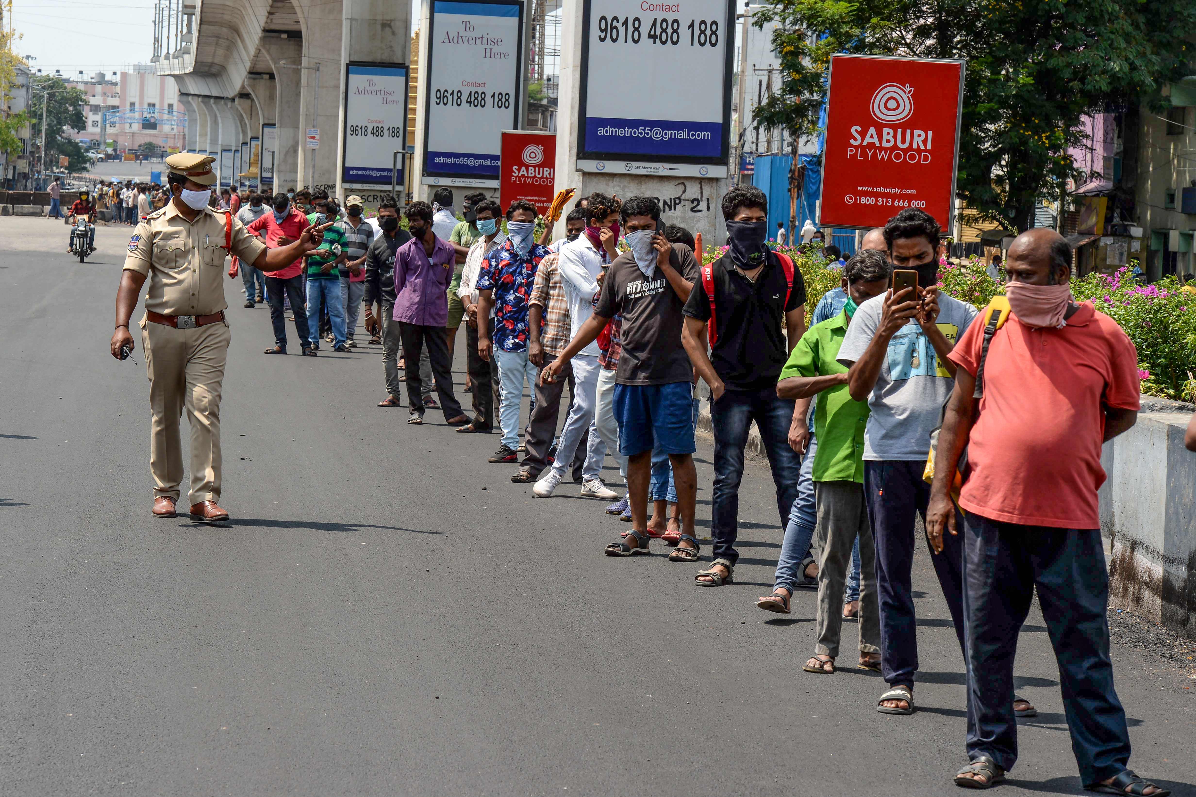 Personel polisi berpatroli di sebelah antrean warga di depan toko minuman keras di Secunderabad, kota kembar Hyderabad, Rabu (6/5).