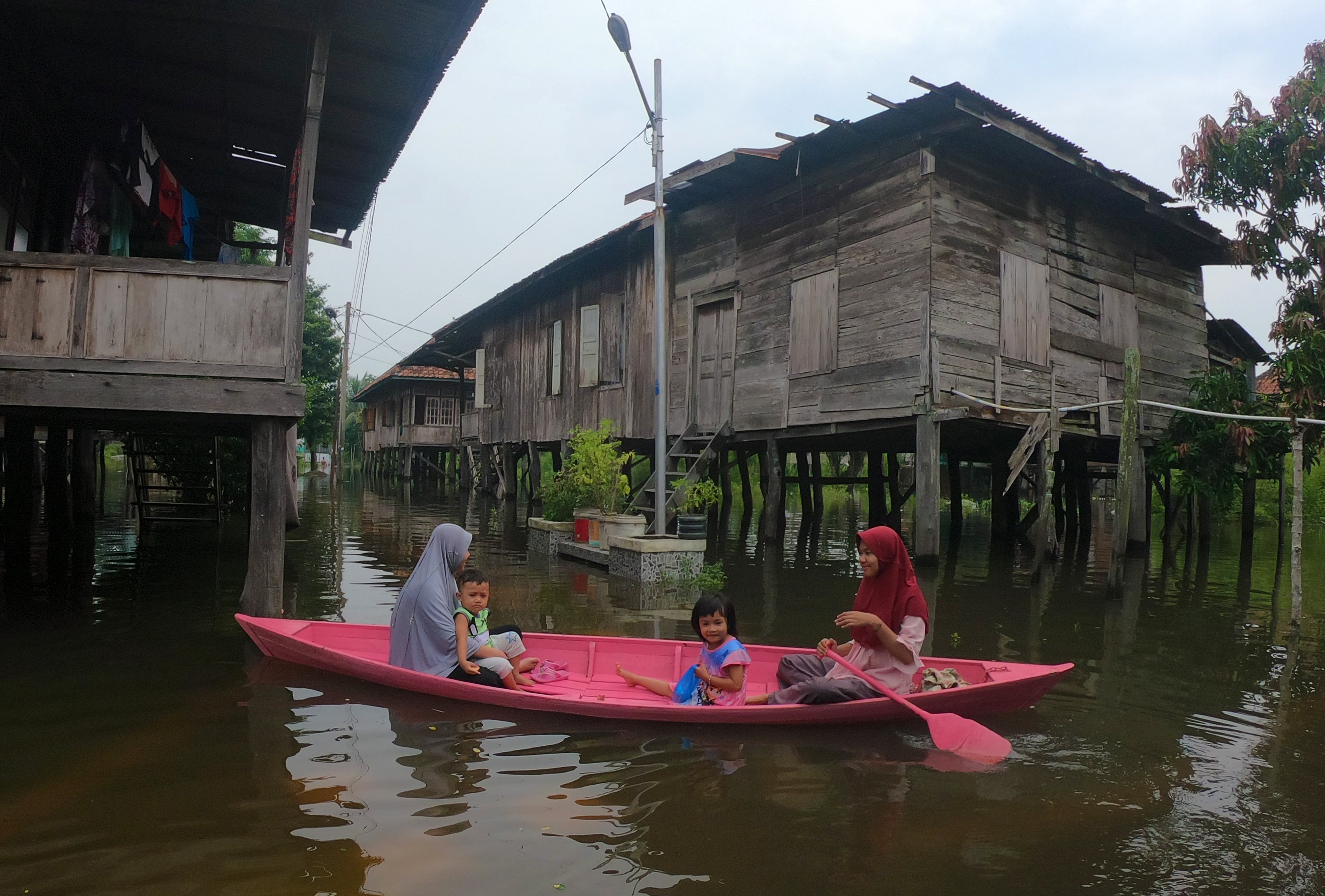 Warga menggunakan perahu untuk melintasi permukiman yang terendam banjir luapan Sungai Batanghari di Mudung Laut, Pelayangan, Jambi, Rabu (6