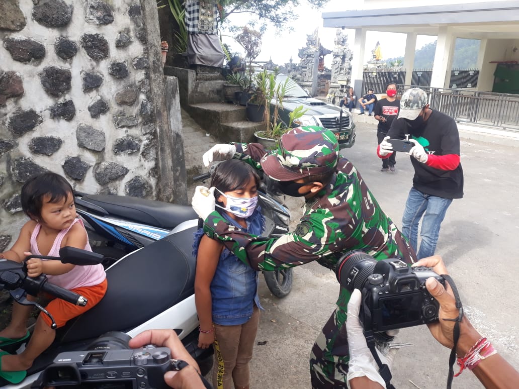 Seorang TNI membantu seorang anak di Banjar Serokadan, Bangli, Bali memakai masker, Sabtu (16/5/2020).